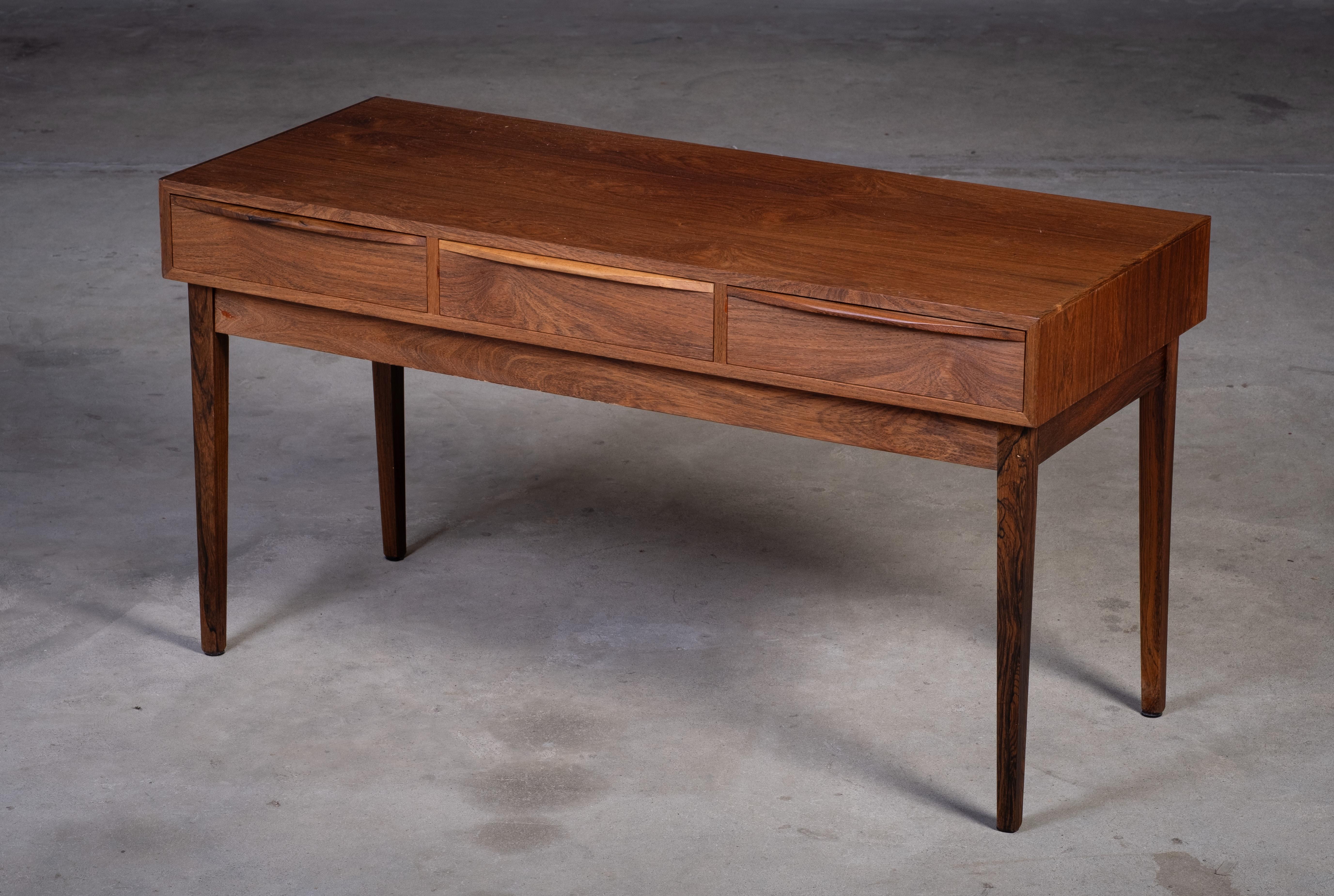 Elegante tavolino o mobile da ingresso in palissandro danese degli anni '60, dotato di tre cassetti per un pratico stoccaggio. Il pezzo presenta bellissime venature e maniglie ben realizzate, che riflettono l'estetica raffinata del design danese di