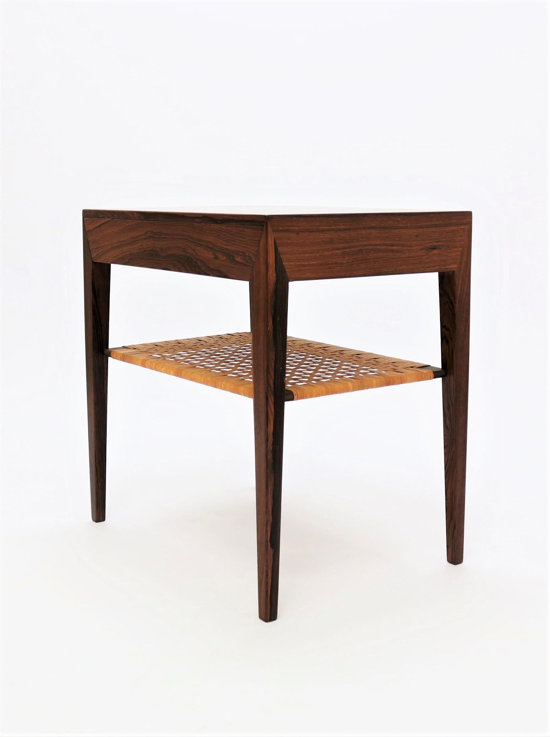 This stunning design was made in the 1950s by Danish Designer Severin Hansen Jr. for Haslev Møbelfabrik (Haslev Furniture), Denmark. The table features an integrated drawer and an elegant shelf in beautifully patinated woven cane. Iconic piece of