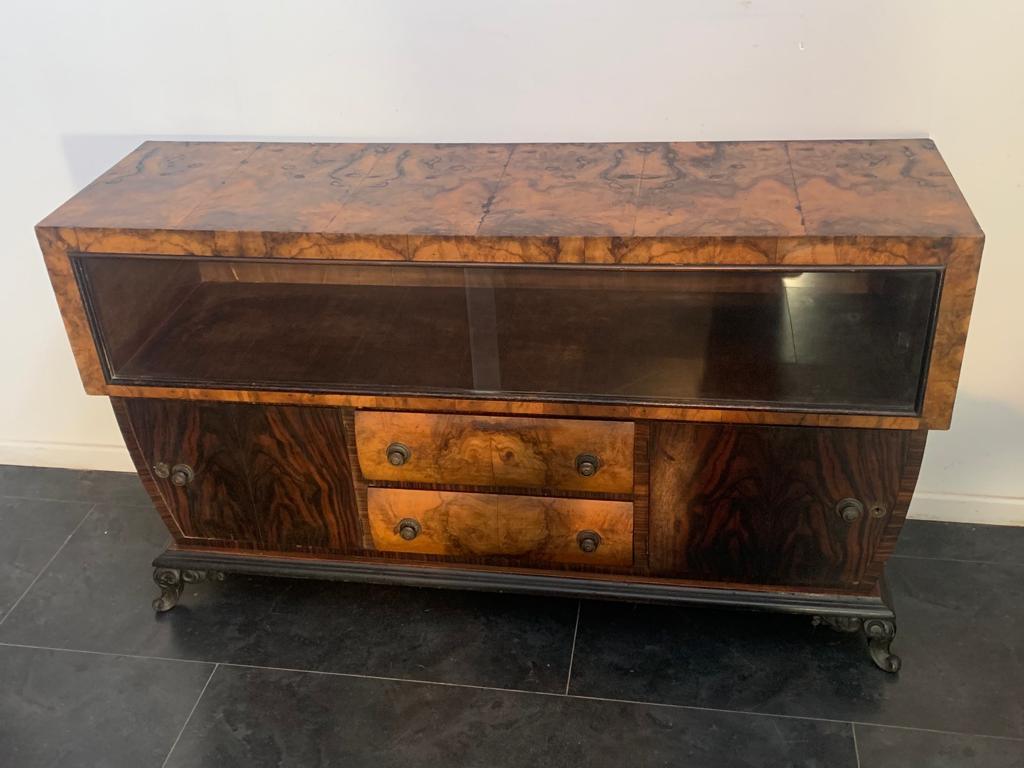 Eclectic art deco sideboard in rosewood and olive burl, the ebonized base ends with 2 finely carved wavy feet. On the front door window compartment with 2 sliding glass. Interesting profile that connects the drawers and doors in ebony maccassar laid