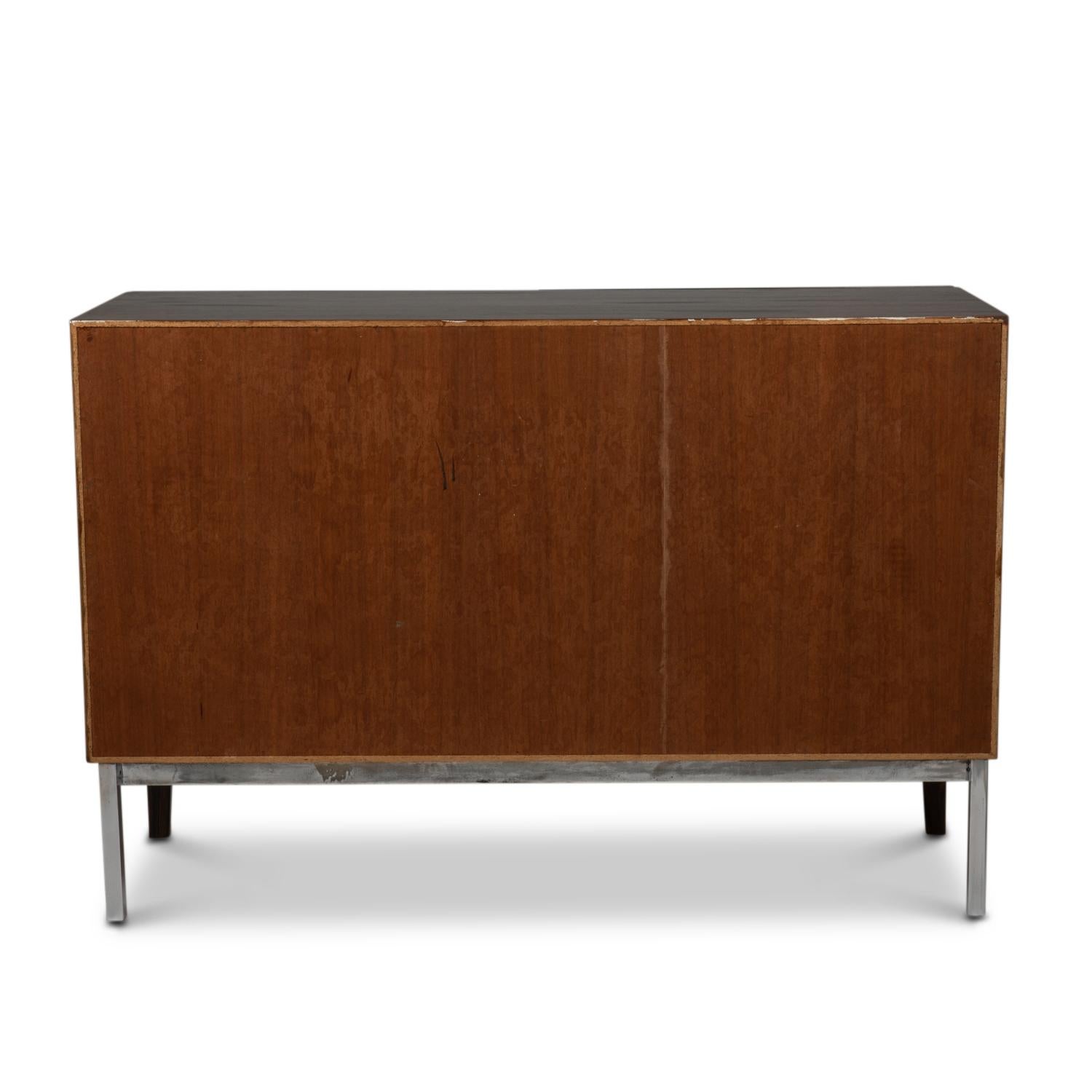 Low rectangular rosewood sideboard, opening with two doors on the front and four drawers inside with their chromed metal handles, two drawers and a shelf, the two drawers and the shelf interchangeable. Spacer bar in chromed metal. 
Dutch work made