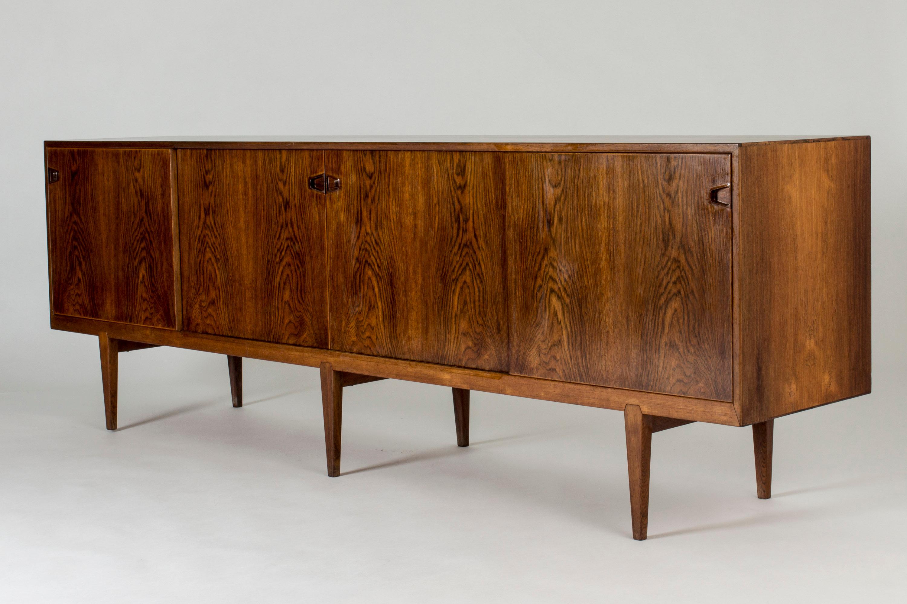 Elegant rosewood sideboard by Henry Rosengren Hansen. Nice details like the joinery of the legs and sculpted handles that meet at the center of the front.