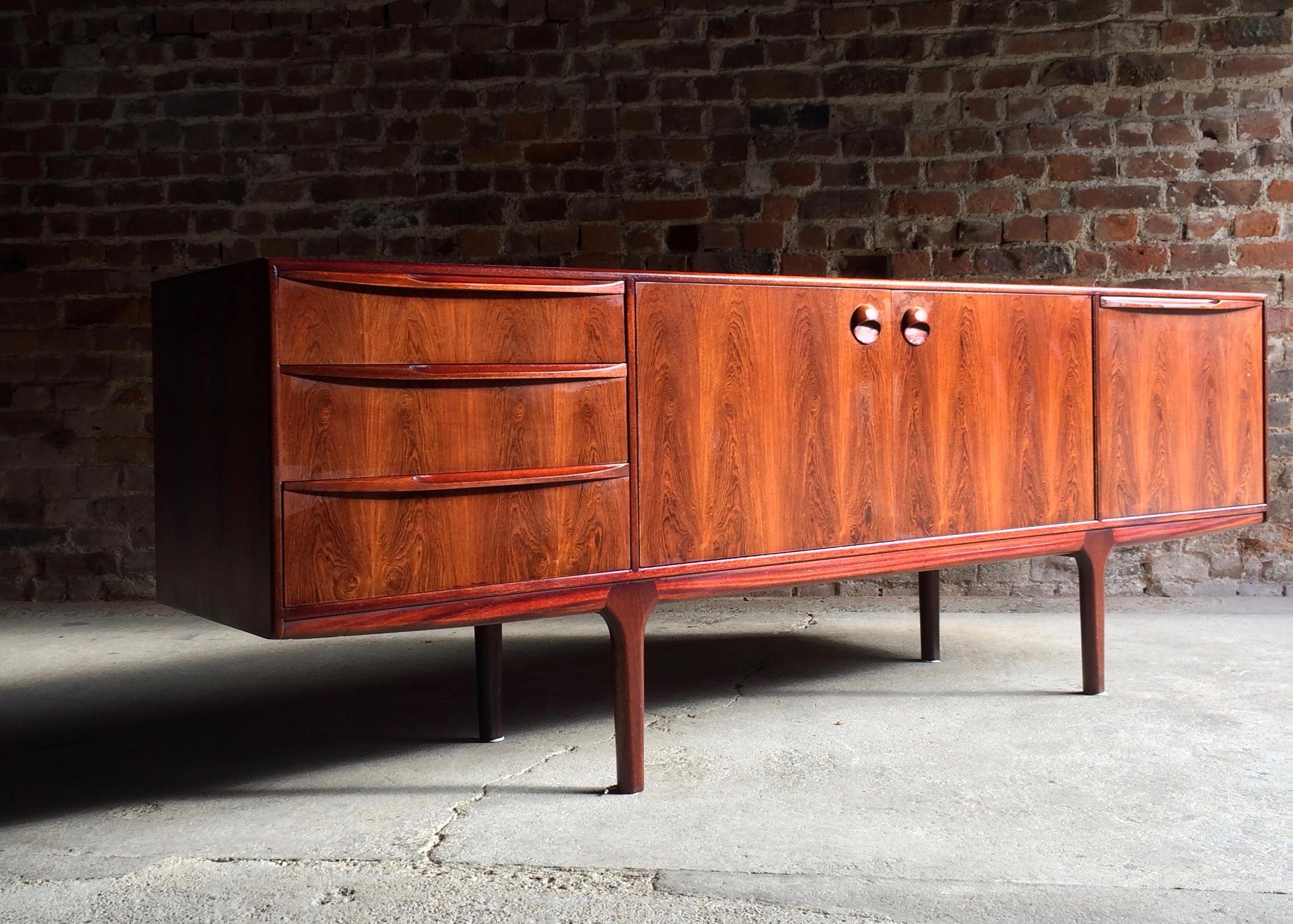 A stunning midcentury design rosewood sideboard credenza designed by Tom Robertson for AH McIntosh of Kirkcaldy, Scotland, circa 1960s, the beautiful rectangular top with stunning rosewood grain over centre section double doors with circular door