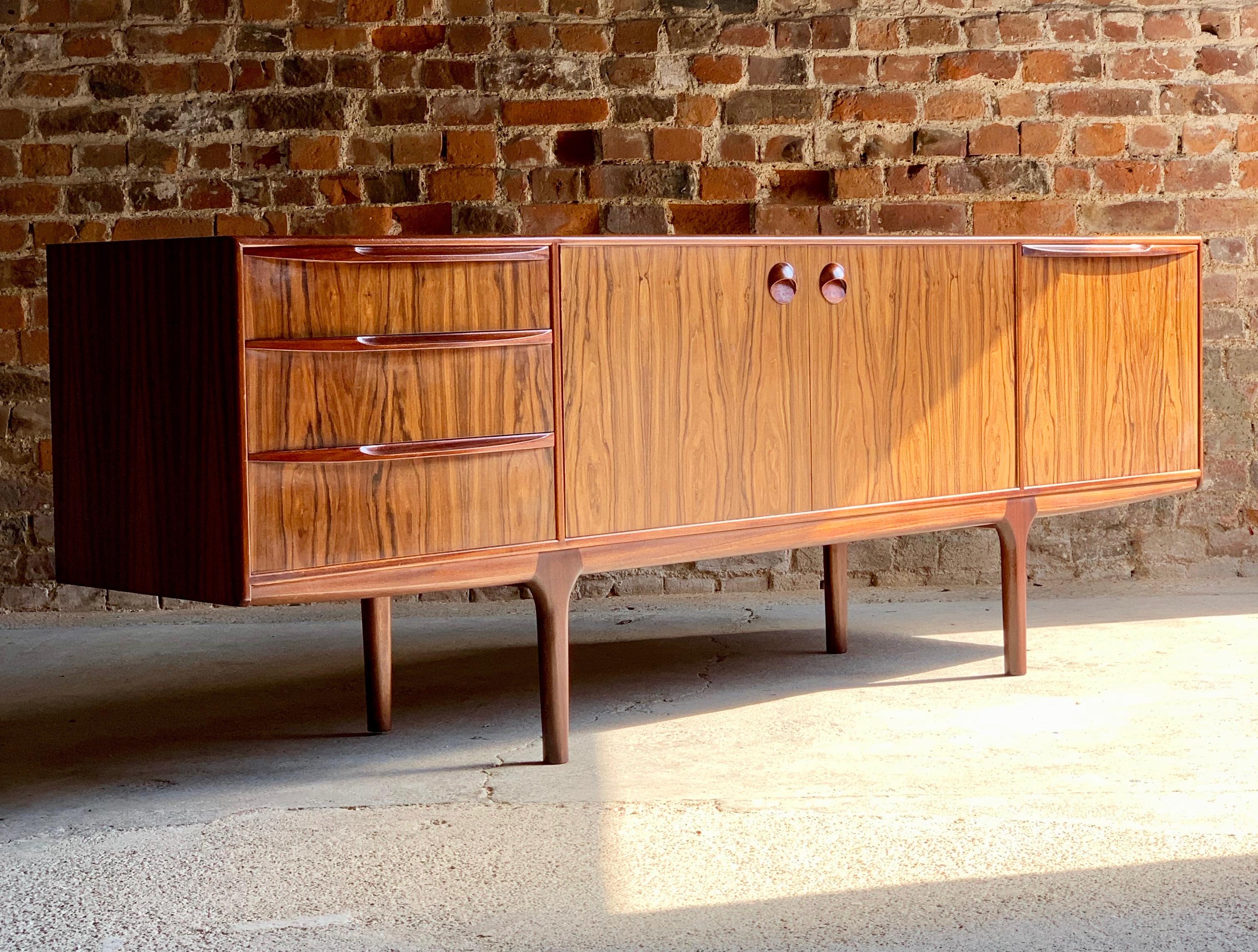 A stunning midcentury design rosewood sideboard credenza designed by Tom Robertson for AH McIntosh of Kirkcaldy, Scotland, circa 1960s, the beautiful rectangular top with stunning rosewood grain over centre section double doors with circular door
