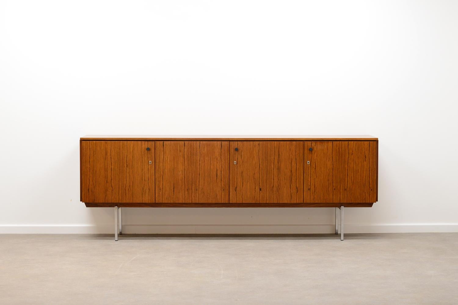 Rosewood sideboard made in germany 1965 by Gebrüder Laker. Rio Rosewood veneer and chrome base. Behind the 4 doors are shelving and two drawers. only the middel lock (with key) is functional, doors close with magnets. In very good vintage condition.