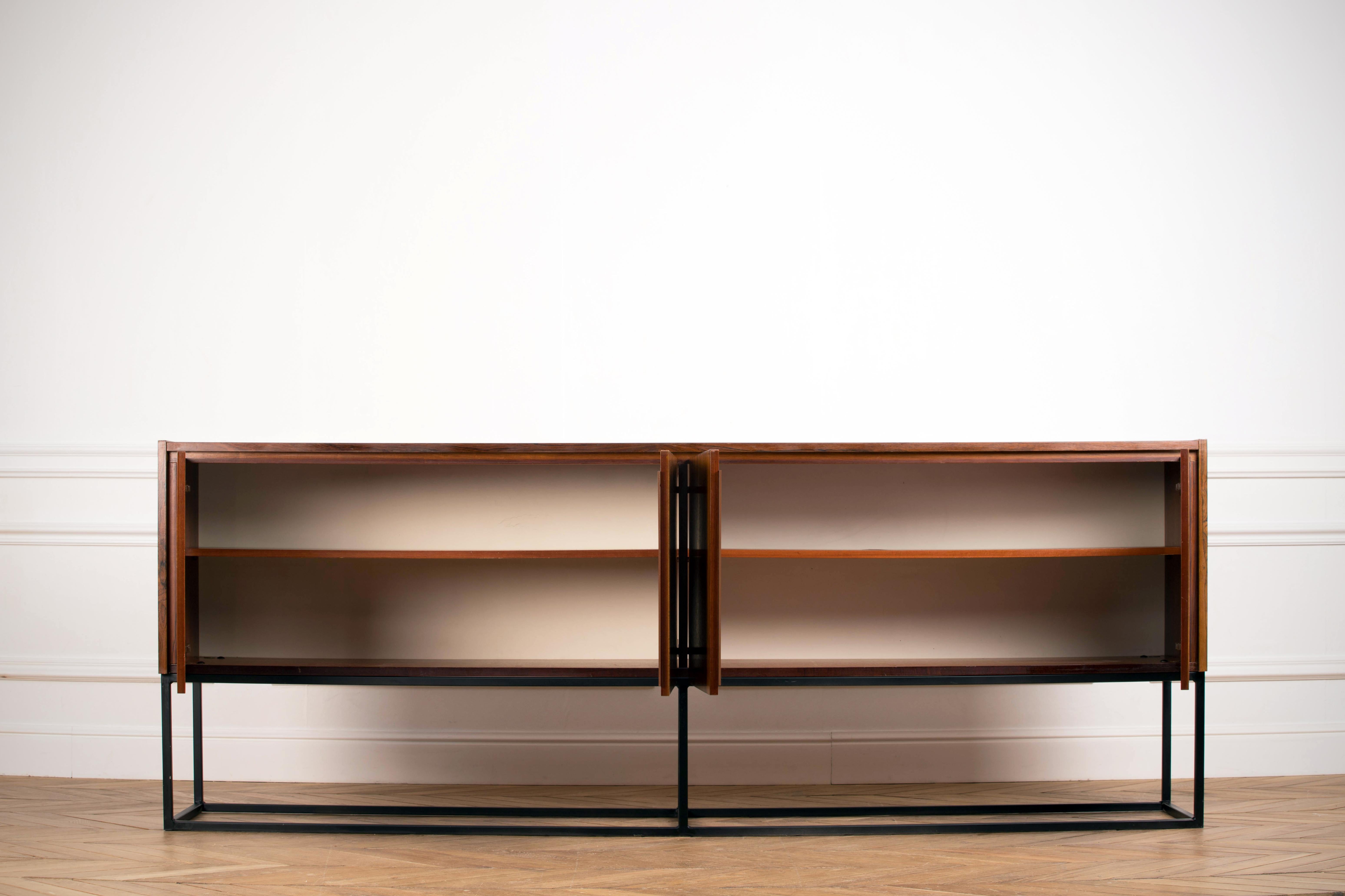 Midcentury rosewood sideboard from the 1960s. It is a shining example of the form and function synonymous with furniture of this era. It has is all ; well-built, great design and heaviness. Four doors hiding storage space. The minimal design and the