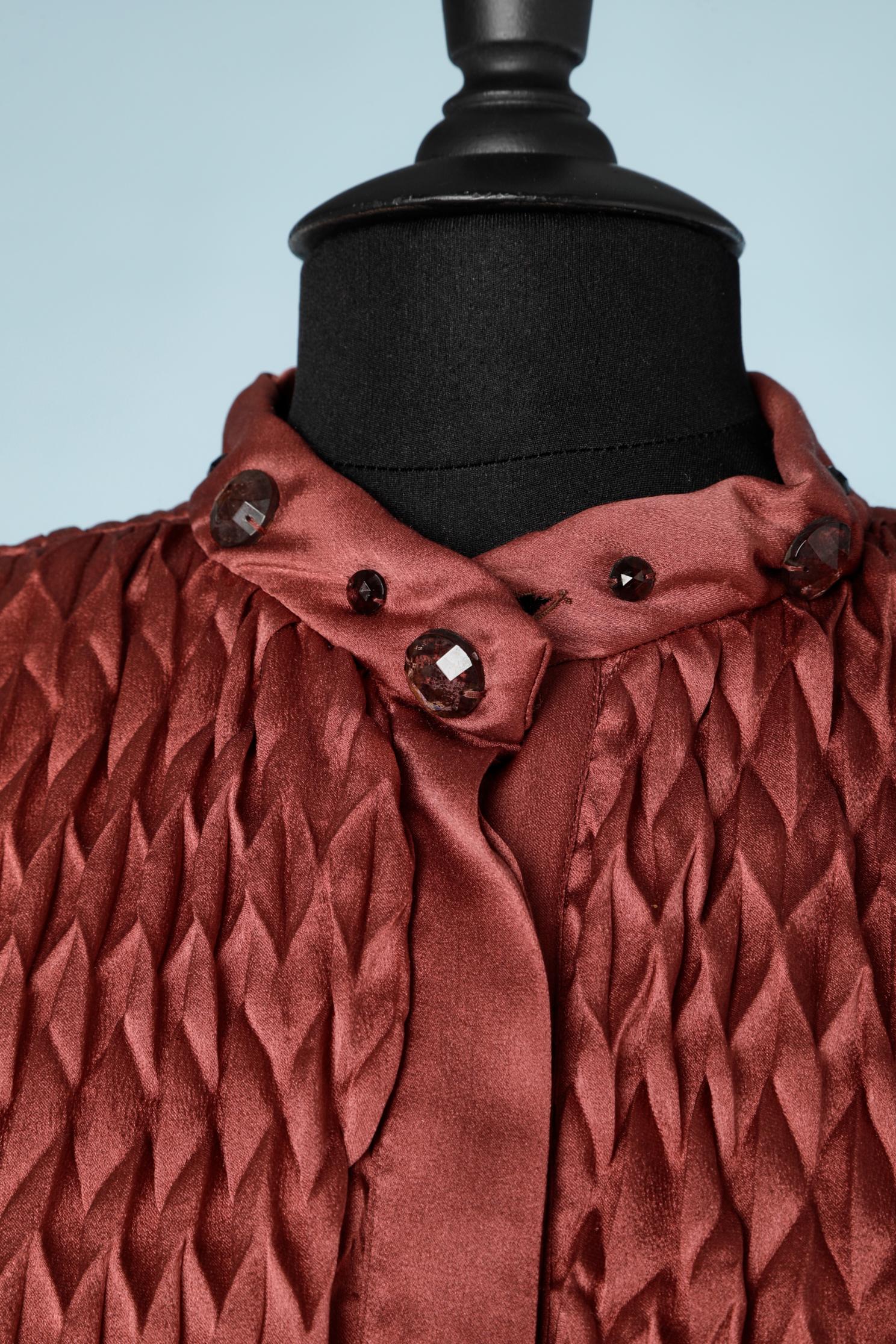 Veste plissée origami en soie palissandre perlée avec cabochons en verre. Col, poignets et ceinture matelassés.
TAILLE M 