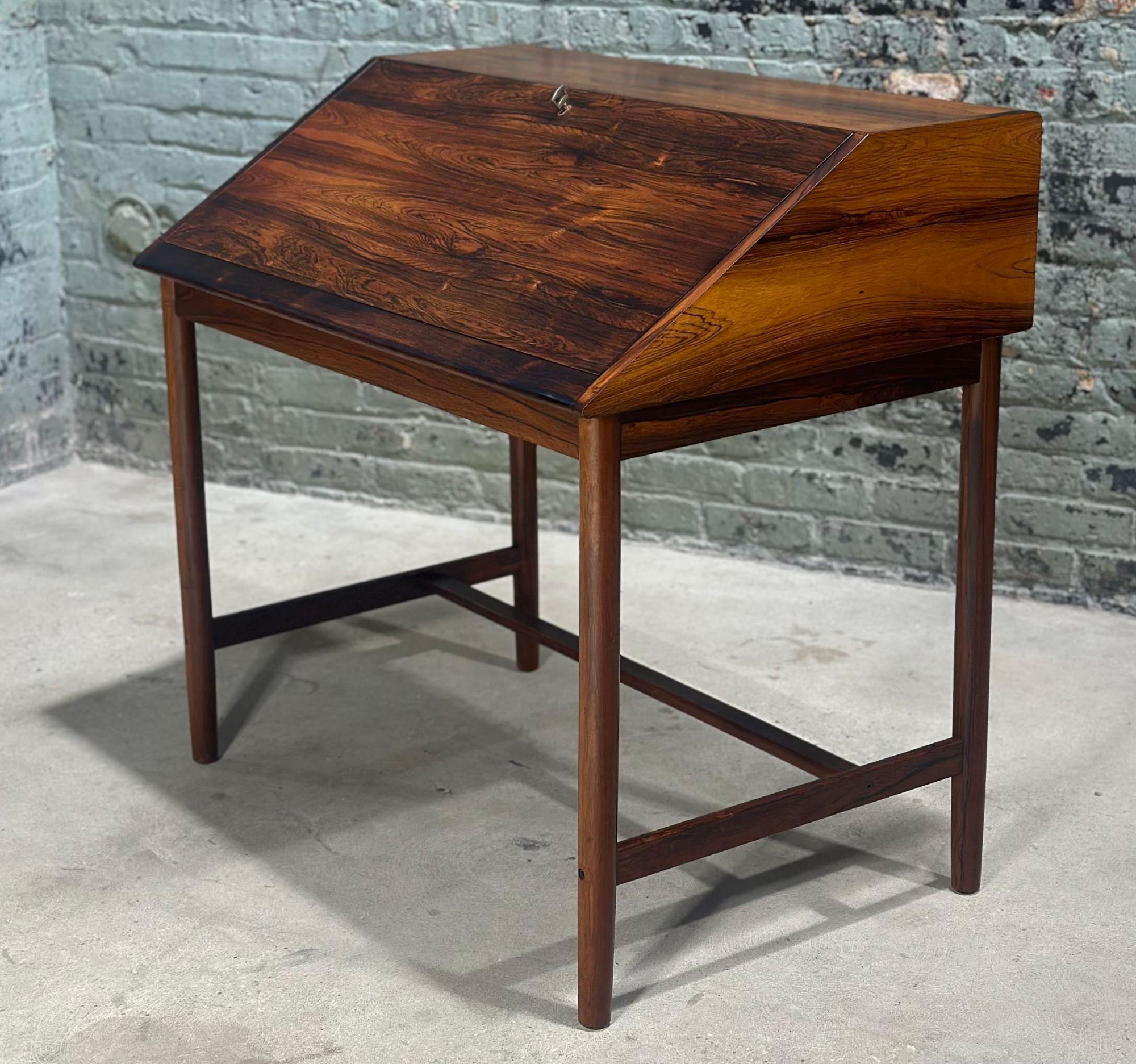 Rosewood Slant Front Desk by Sykky Iven Blode Blindheim, Norway 1960. Desk is in excellent condition, has the original key. Desk has 4 slots and 2 drawers. Desk is signed on bottom
Measures 37