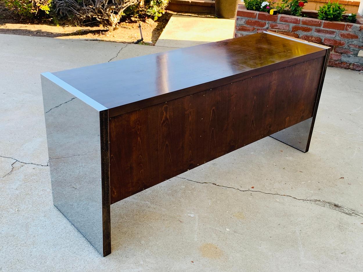 Roger Sprunger for Dunbar rosewood and stainless steel executive credenza dating from the early 1970s.

 The credenza has generous storage having 2 file cabinets and 3 center drawers.

Measurements:
61 inches wide x 18.25 inches deep x 27.5