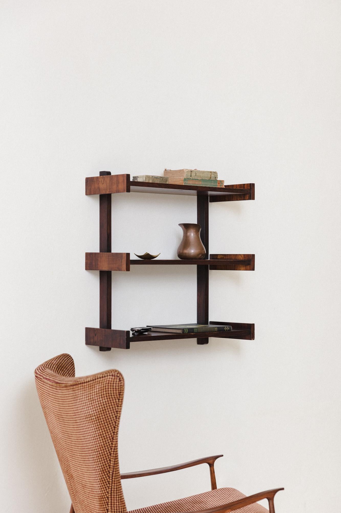 This charming bookshelf, manufactured by Celina Decorações in the 1960s, is composed of a solid wood structure with Rosewood veneers. The piece is composed of a structure with three shelves, and attaches to the wall through a single point – a very