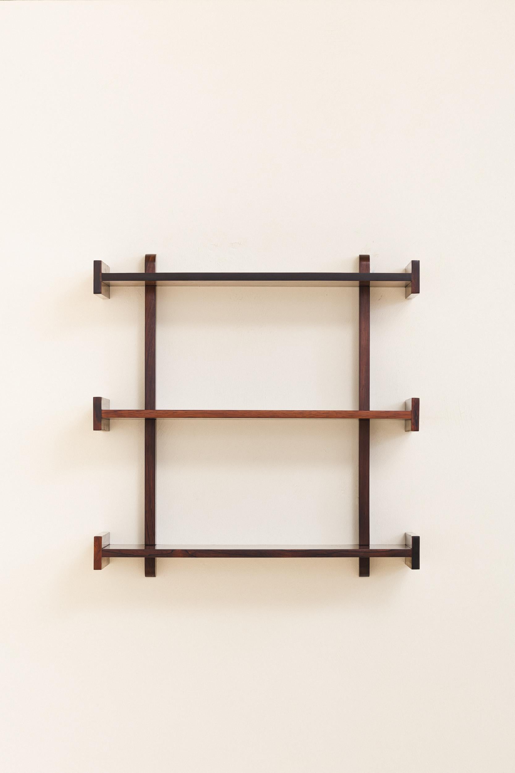 Dieses in den 1960er Jahren von Celina Decorações hergestellte Wandregal hat ein minimalistisches Design, das durch seine schönen Palisanderfurniere noch verstärkt wird. Er verfügt über drei Ablagen mit T-förmigen seitlichen Details, die sowohl für