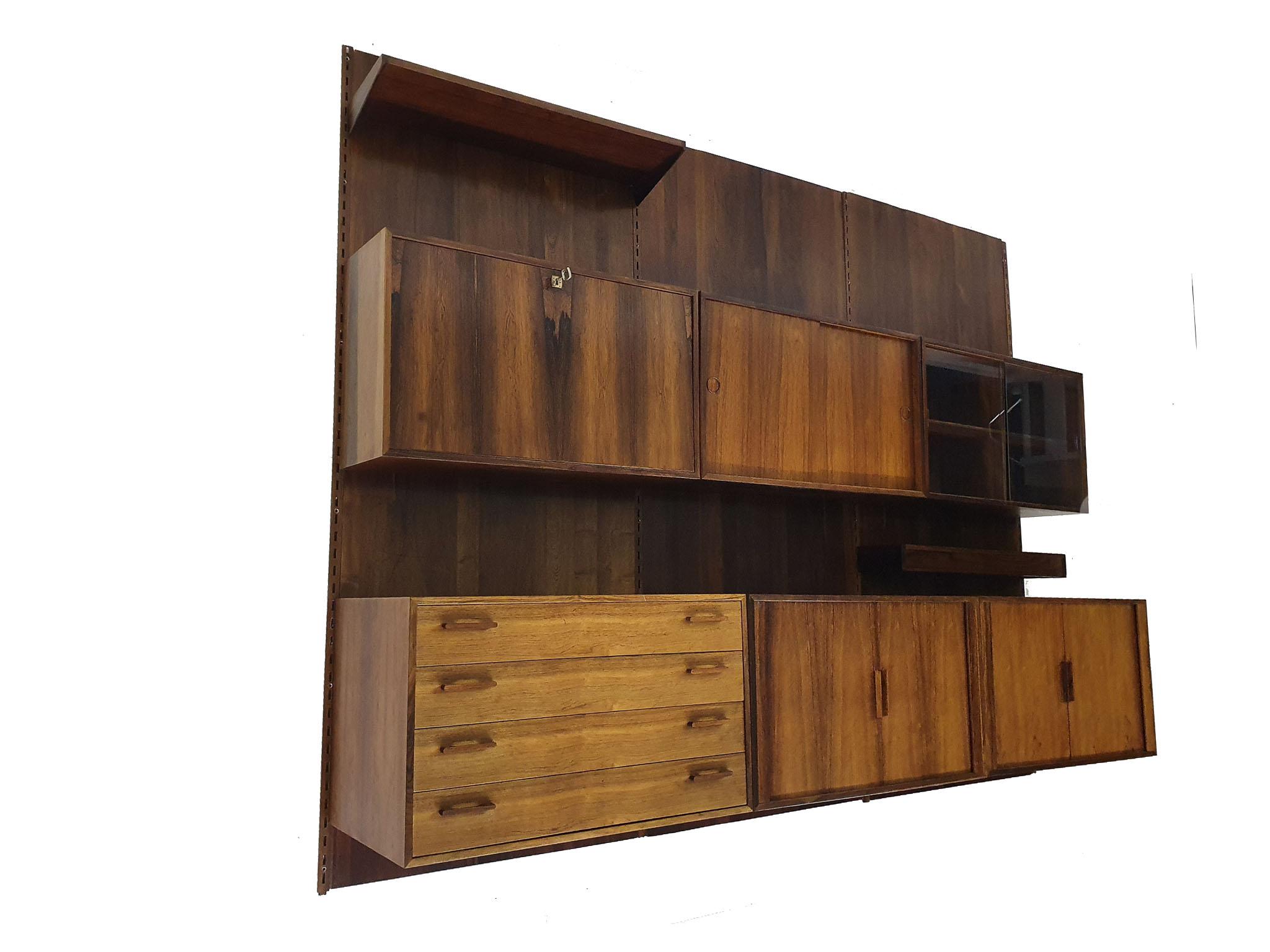 Large rosewood wall unit with rosewood back plates.
The cabinet has some traces of use like stains, but no veneer damage.
There are 2 holes in the back plates, one for the lamp and a larger one which is damaged, but not visisble when the cabinet