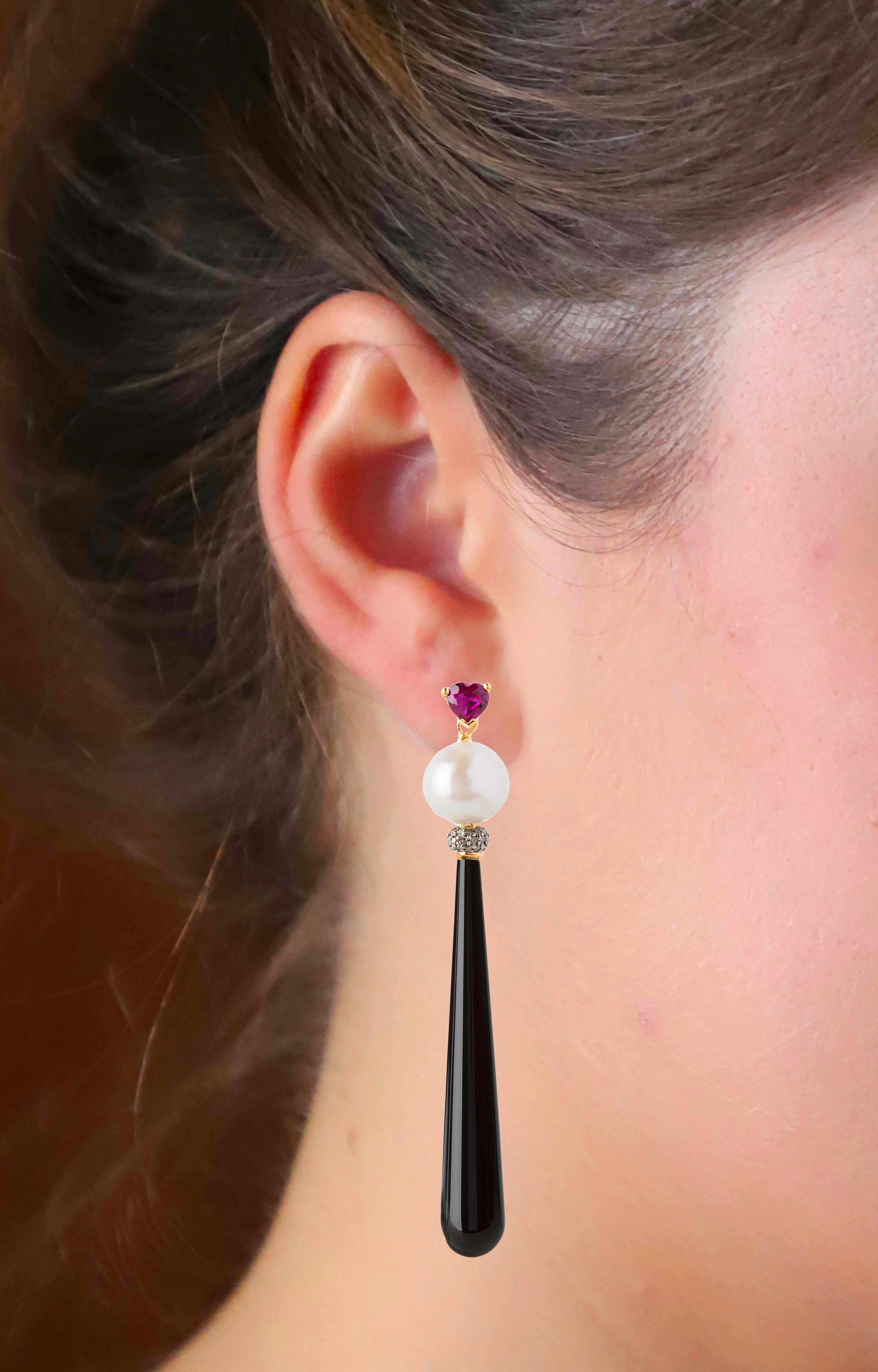 Handcrafted by Rossella Ugolini, these exquisite Deco style earrings in 18K Yellow Gold are an alluring display of elegance. 
The design features a heart-shaped Ruby on the lobe, paired with a white Pearl and a sleek, long drop of black Onyx adorned