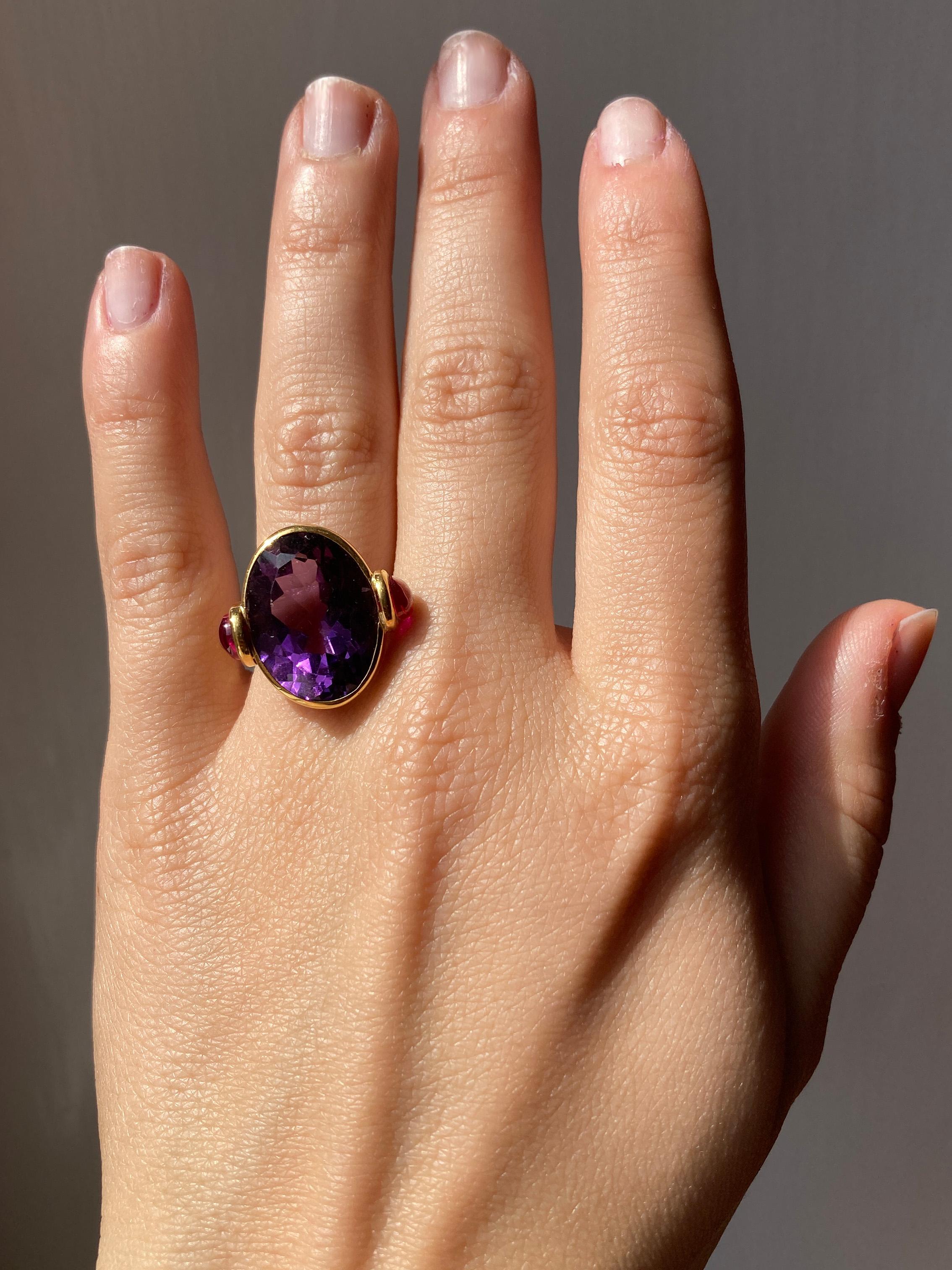 Rossella Ugolini 18k Gelbgold Oval Amethyst 1 Karat Rubine Cocktail Ring Made in Italy.
Dieser atemberaubende Cocktailring zeigt einen tiefvioletten ovalen Amethysten, der elegant in eine Lünette aus 18 Karat Gelbgold gefasst ist. Zwei runde Rubine