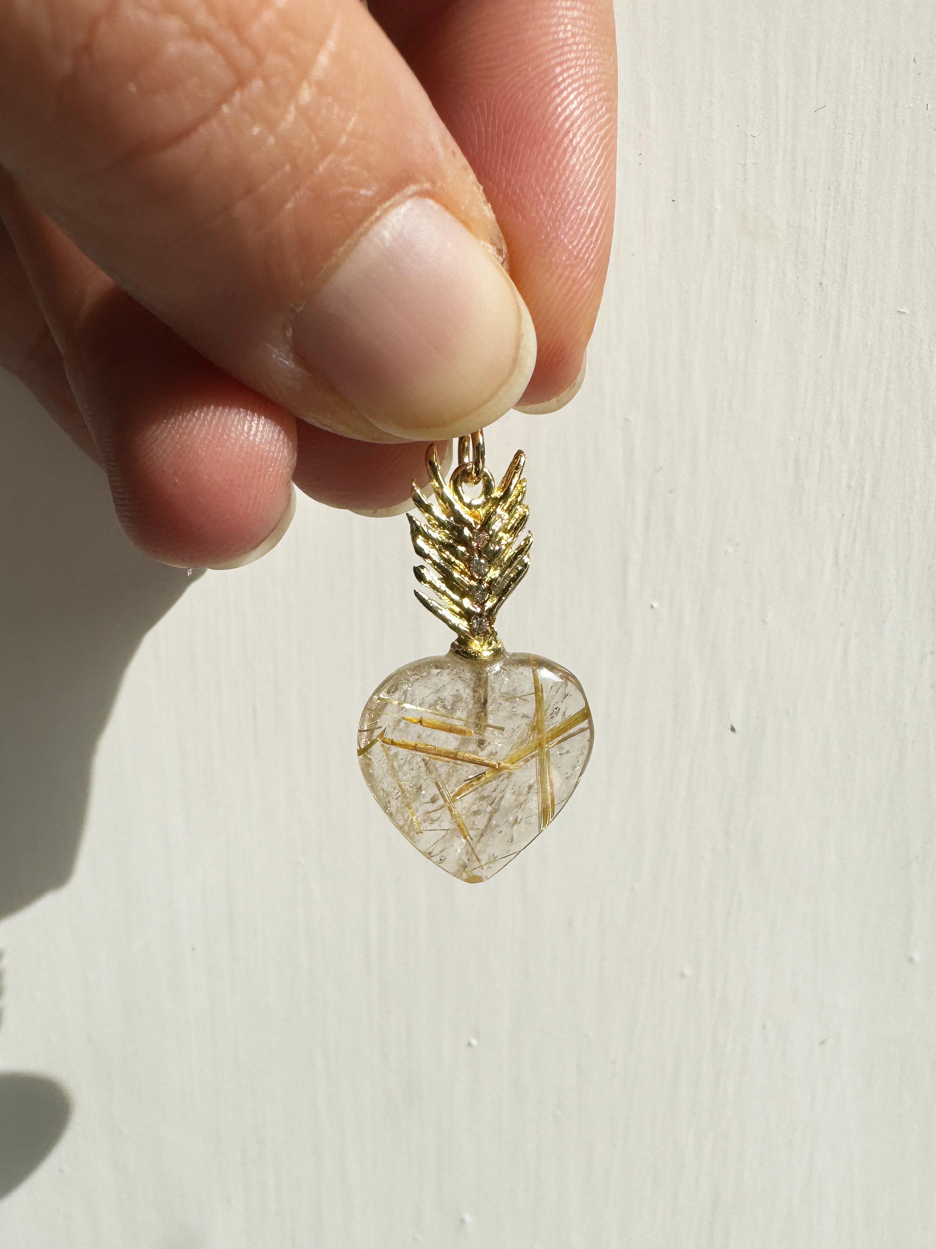 Rossella Ugolini, or jaune 18 carats  Charm unisexe en forme de cœur en quartz rutilé et diamants blancs. Dimension : longueur en 1,14 x diamètre en 0,62  (cm 2,9x cm 1,6).  Breloque en or jaune 18k réalisée en Italie, présentant un quartz rutilé en