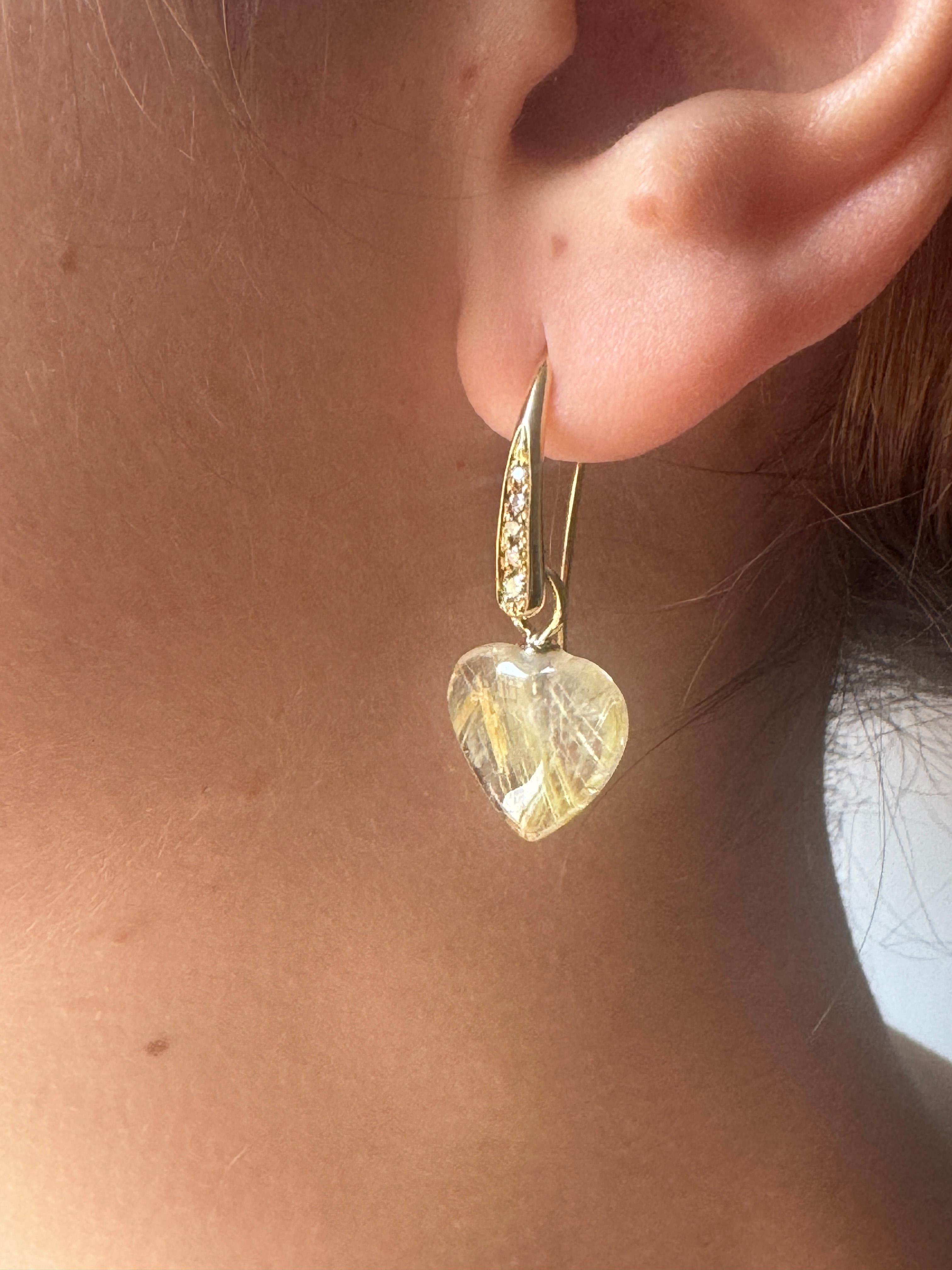Disponibles dès maintenant, ces boucles d'oreilles sentimentales sont réalisées en or jaune 18 carats et mettent en scène des pierres de quartz rutile en forme de cœur suspendues à d'élégants crochets en diamant blanc. Chaque crochet est orné de 5