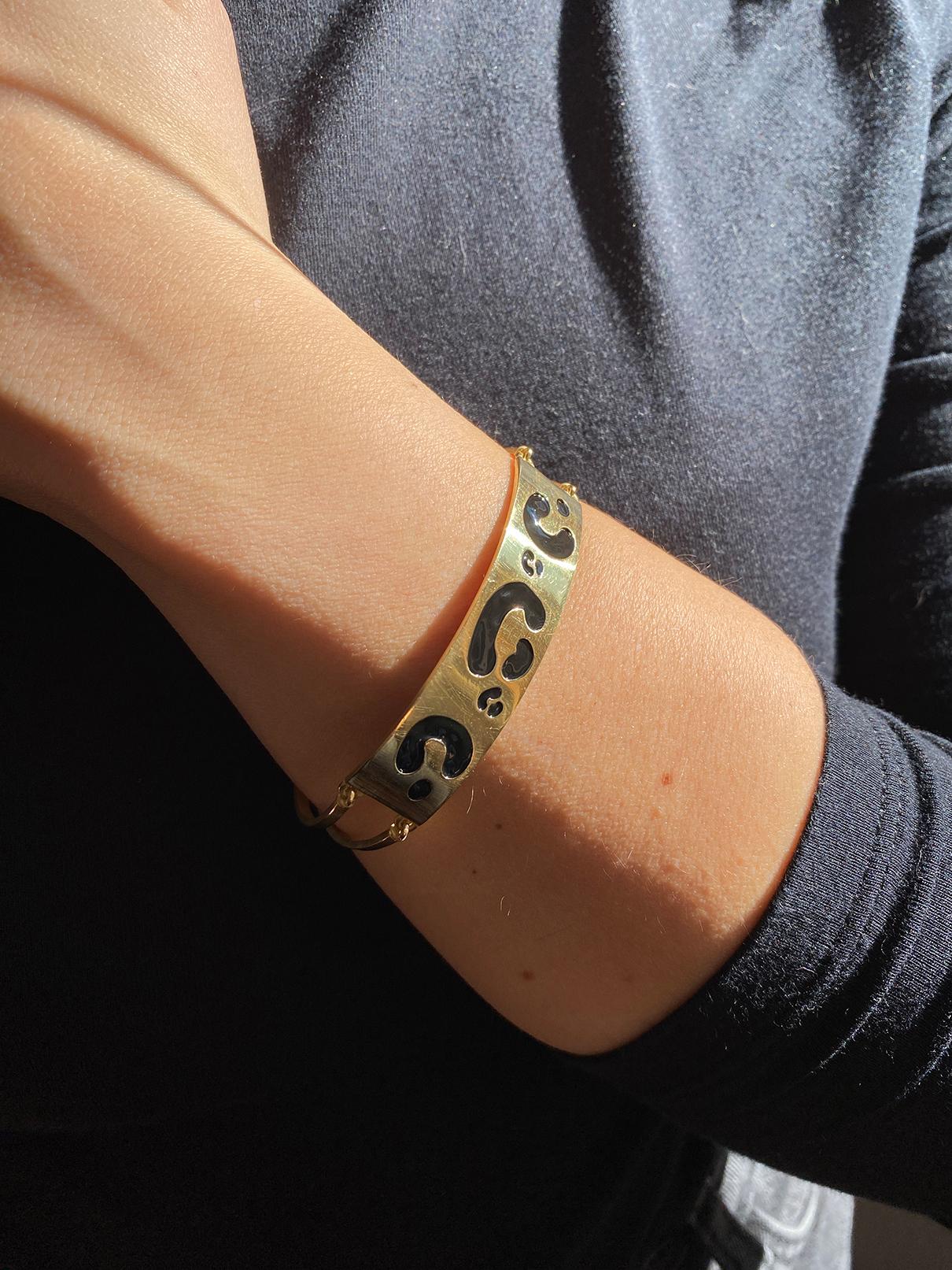 Unisex Cuff bracelet handcrafted from 18K yellow gold Spotted with black enamel. A bold, rectangular 18K yellow gold band graces the top of the wrist, adorned with a unique black enamel spotted pattern. 
8 inches (20 cm in length), resizable on