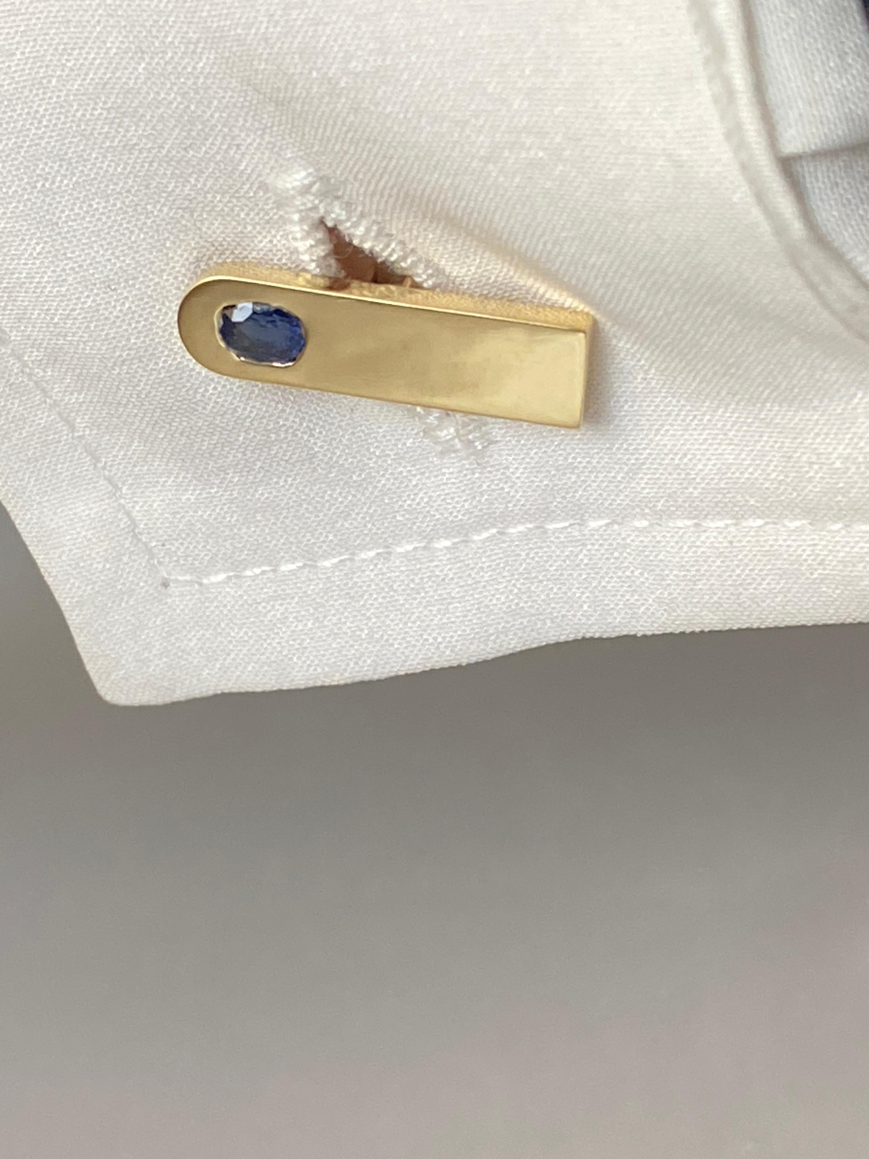Questi gemelli in oro giallo 18 carati, impreziositi da zaffiri blu ovali, sono un bellissimo mix di design moderno e classico. Realizzati a mano in Italia, i gemelli sono caratterizzati da un'elegante barra in oro giallo 18 carati lucido con un