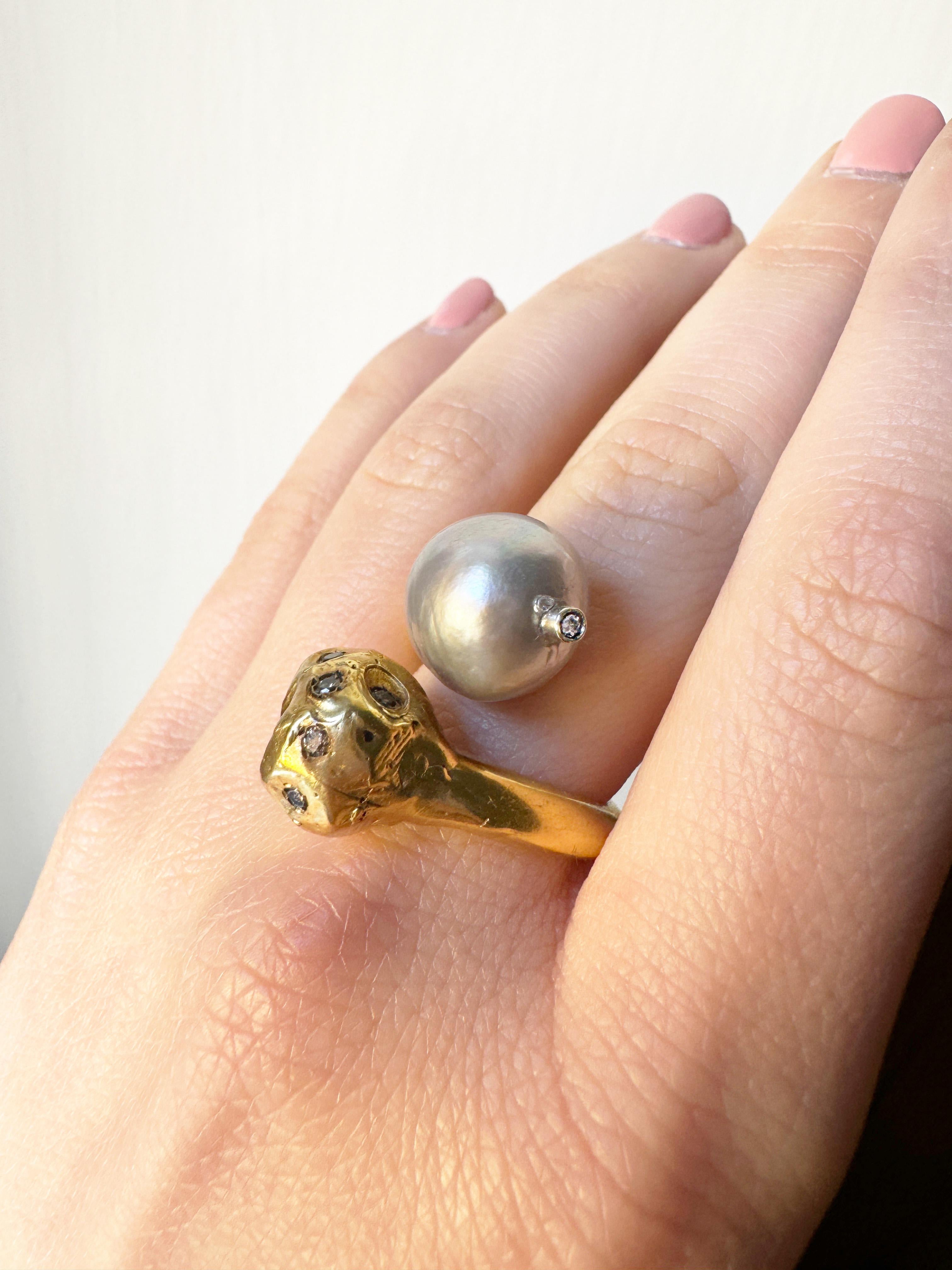 Bague contraire en argent sterling plaqué or jaune 24 carats par Rossella Ugolini. Taille USA 7/ FRA 54
Fabriquée à la main en Italie, la bague présente une sphère martelée irrégulièrement sertie de diamants gris et une perle grise en face d'elle.