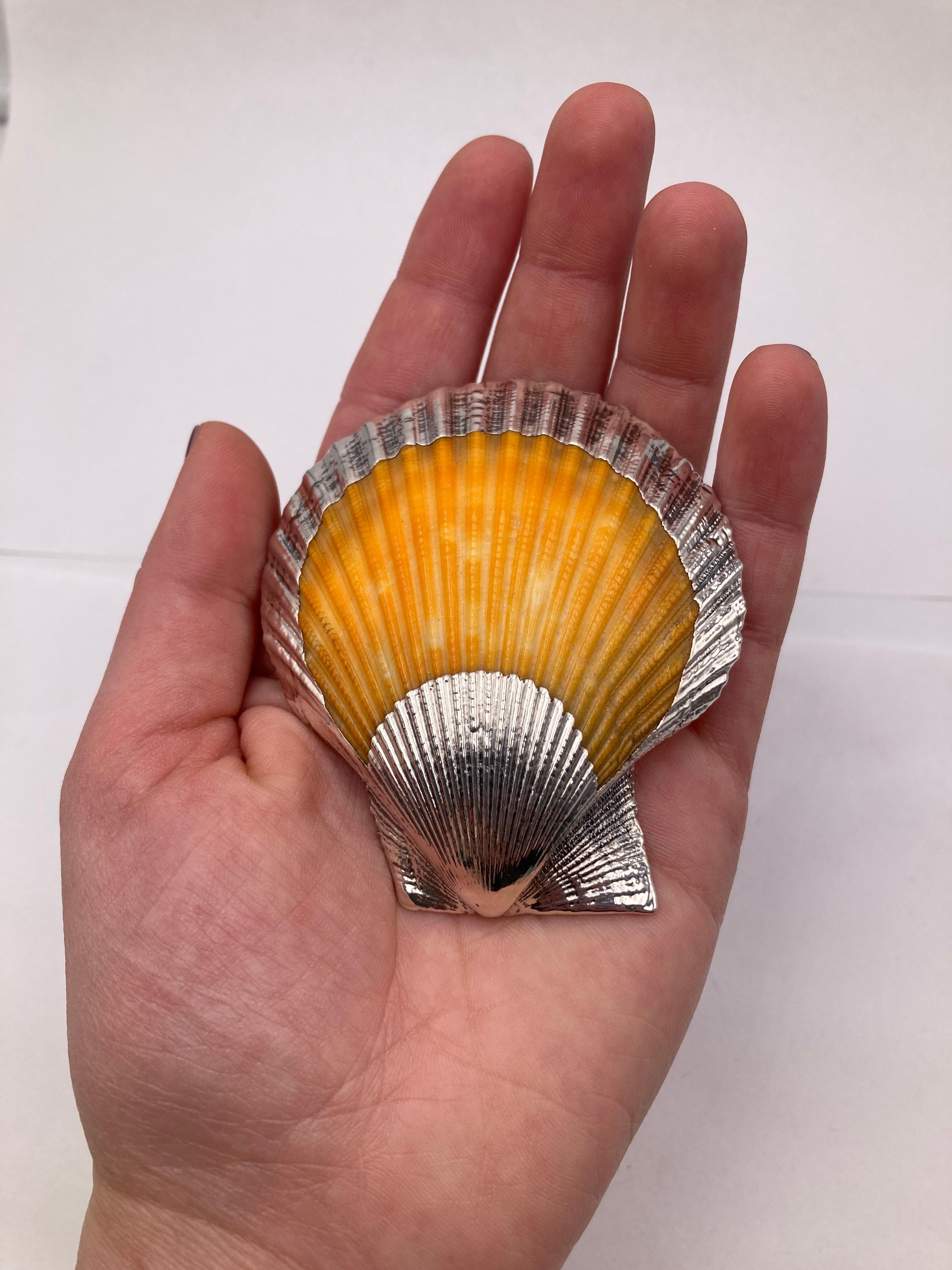 CIRCA 1980 Einzigartiges Schreibtisch-Accessoire Silberschale.
Abmessungen: 6,5 x 7,0 cm
Eine natürliche Muschel aus den 80er Jahren, zart umhüllt von Silber, präsentiert sich als zeitloser Schatz. Muschelmotive, die mit ihren leuchtenden Orange-