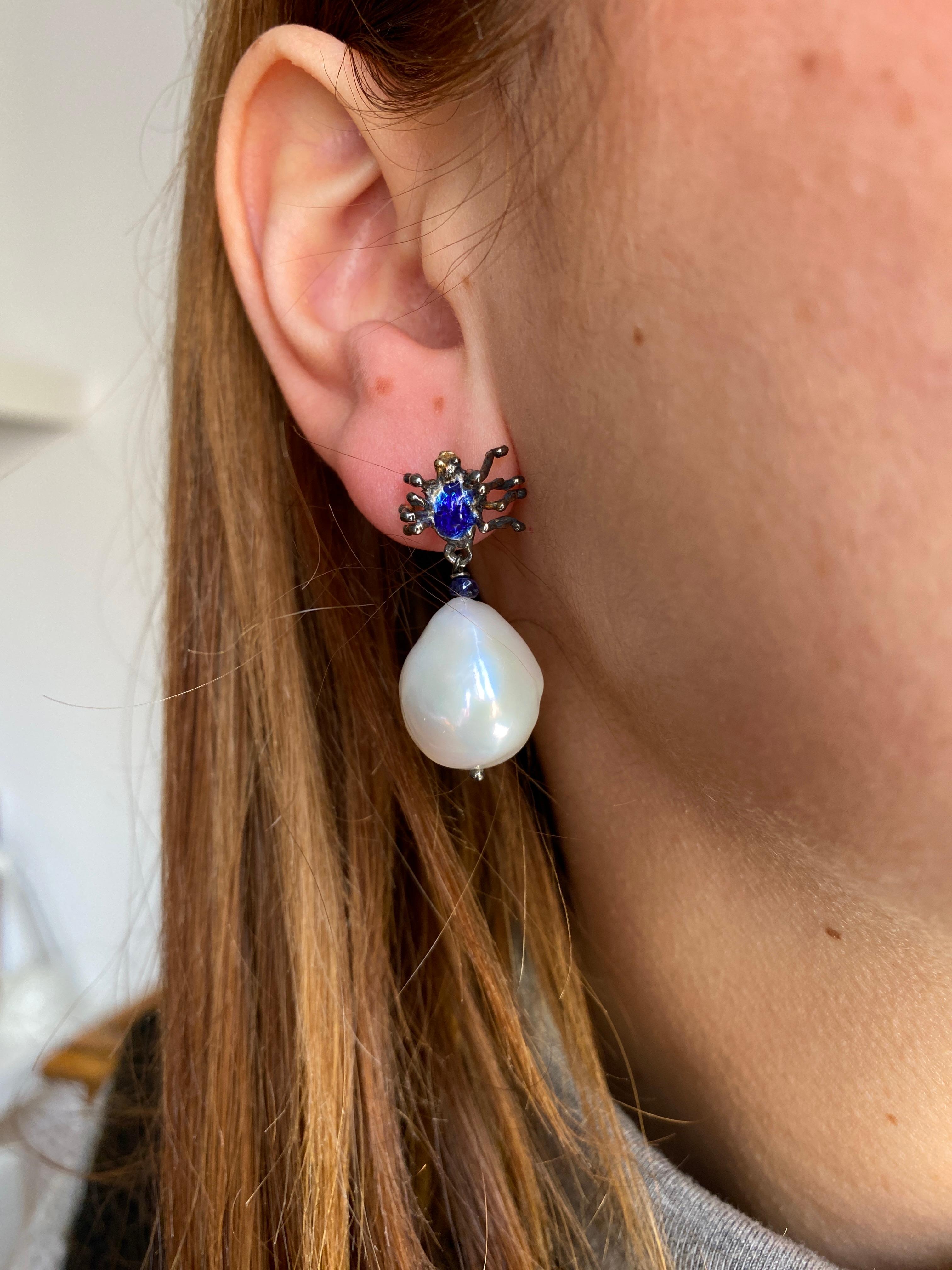 Rossella Ugolini presents a pair of earrings Handcrafted in burnished 18K white gold and hand-glazed in a mesmerizing vivid blue hue.
These earrings feature a unique spider design suspended on the earlobe, the spider elegantly dangles a sapphire