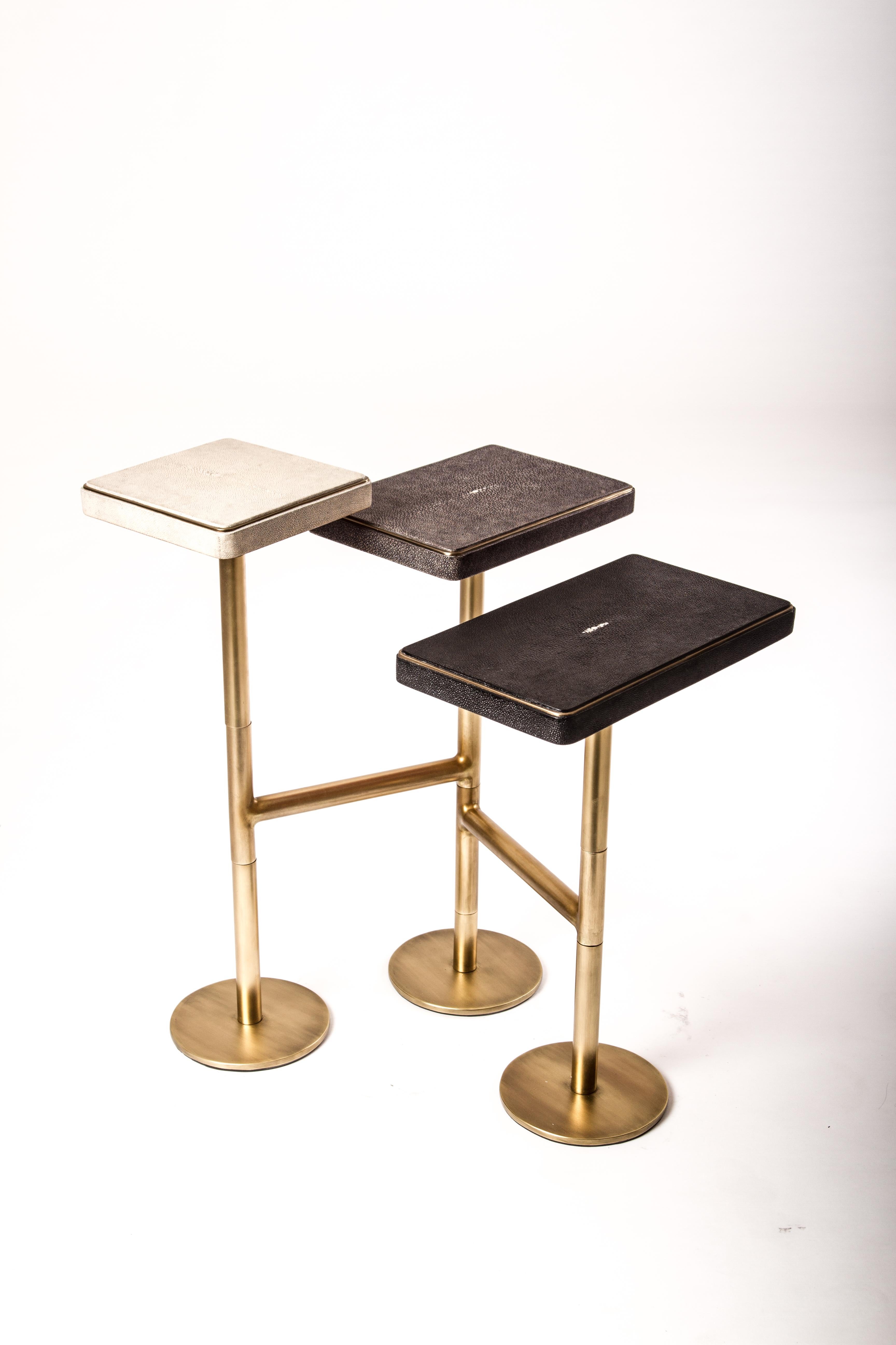 The 3-top rotating side table in cream shagreen, grey-blue shagreen and coal black shagreen is completely mobile, allowing one to adjust the piece to their preference from elongated to clustered. The shagreen inlaid tops have a discreet metal border