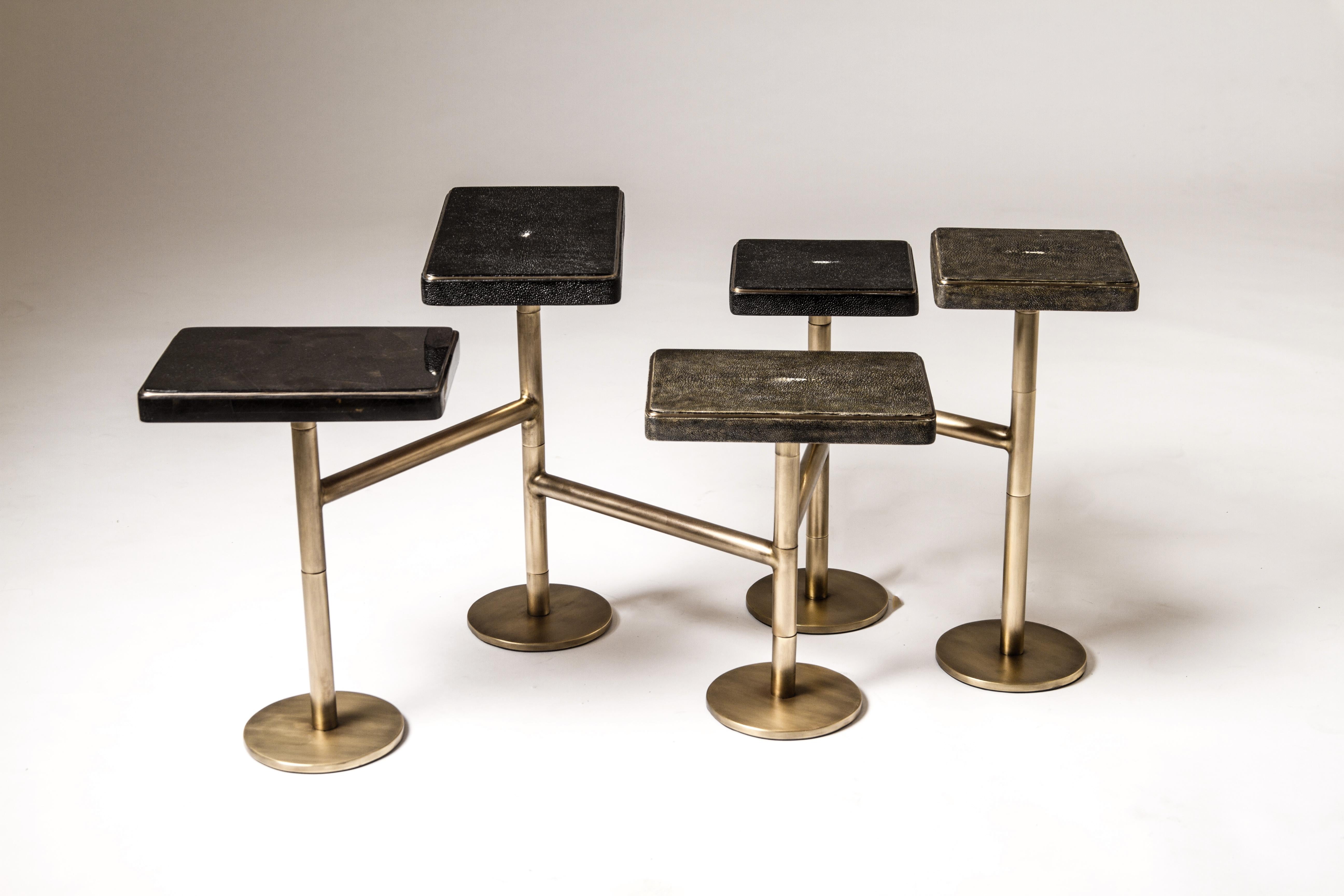 The 5-top rotating coffee table in antique black shagreen, jet black shagreen and black pen shell is completely mobile, allowing one to adjust the piece to their preference from elongated to clustered. The shagreen inlaid tops have a discreet metal