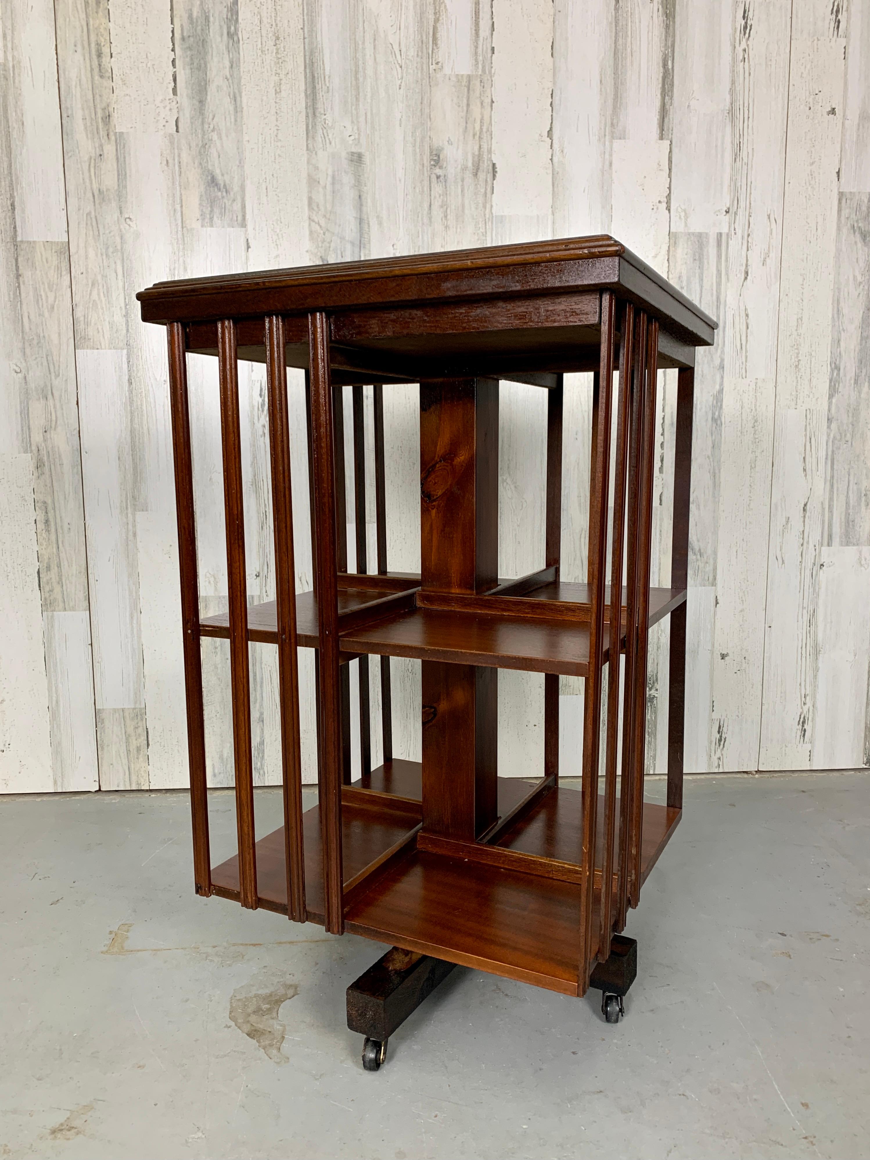 Mahogany antique style swivel bookcase with marquetry shell design on top and cross banding border, mounted on a revolving stand with casters for mobility. Cubbies are 10 3/4 high x 6.5 deep x 10 wide. 