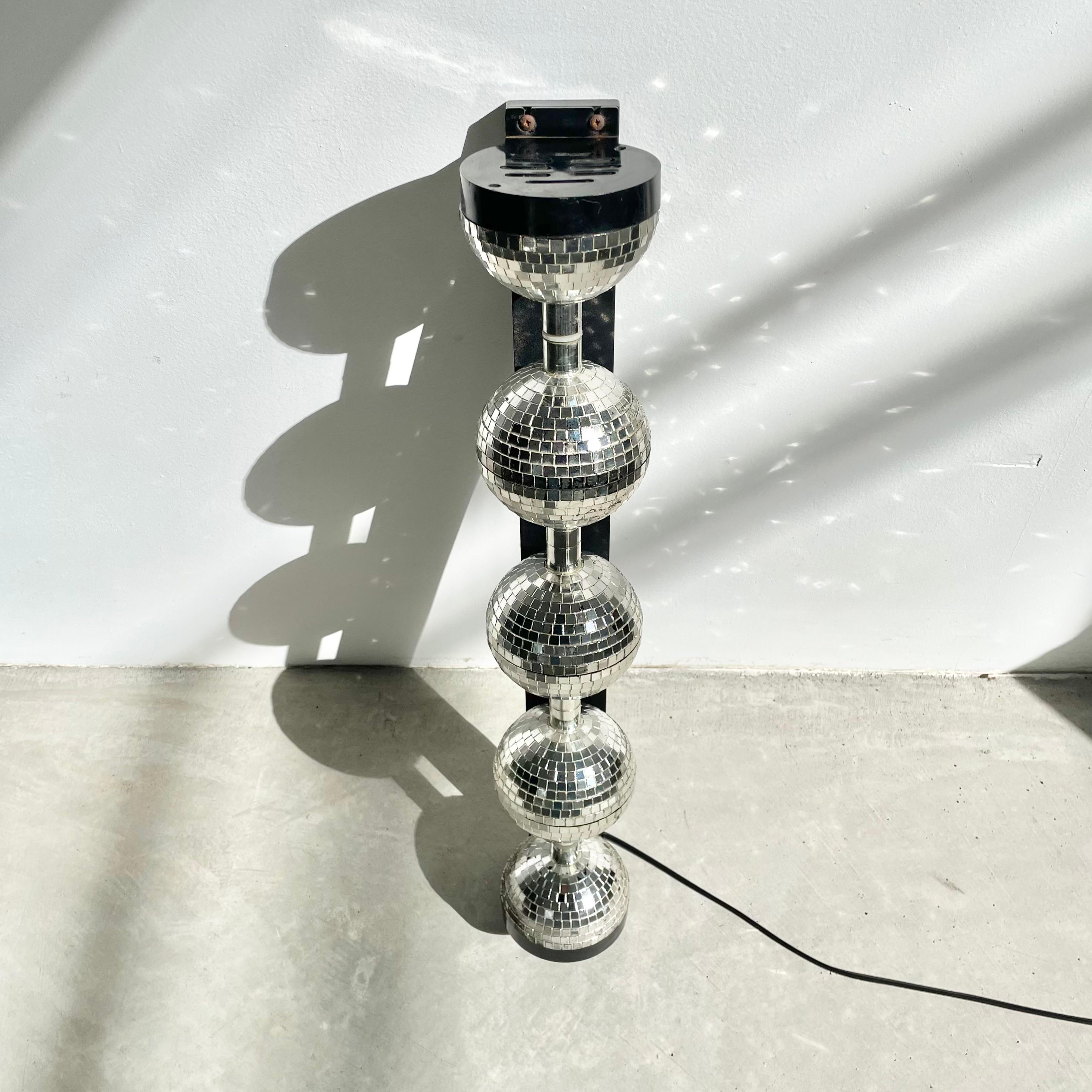 Great vintage rotating disco ball display made of plastic with a metallic paint resembling mirrored glass. The three disco balls in the middle are connected to a small motor in the base that slowly spins the balls giving a great reflection off the