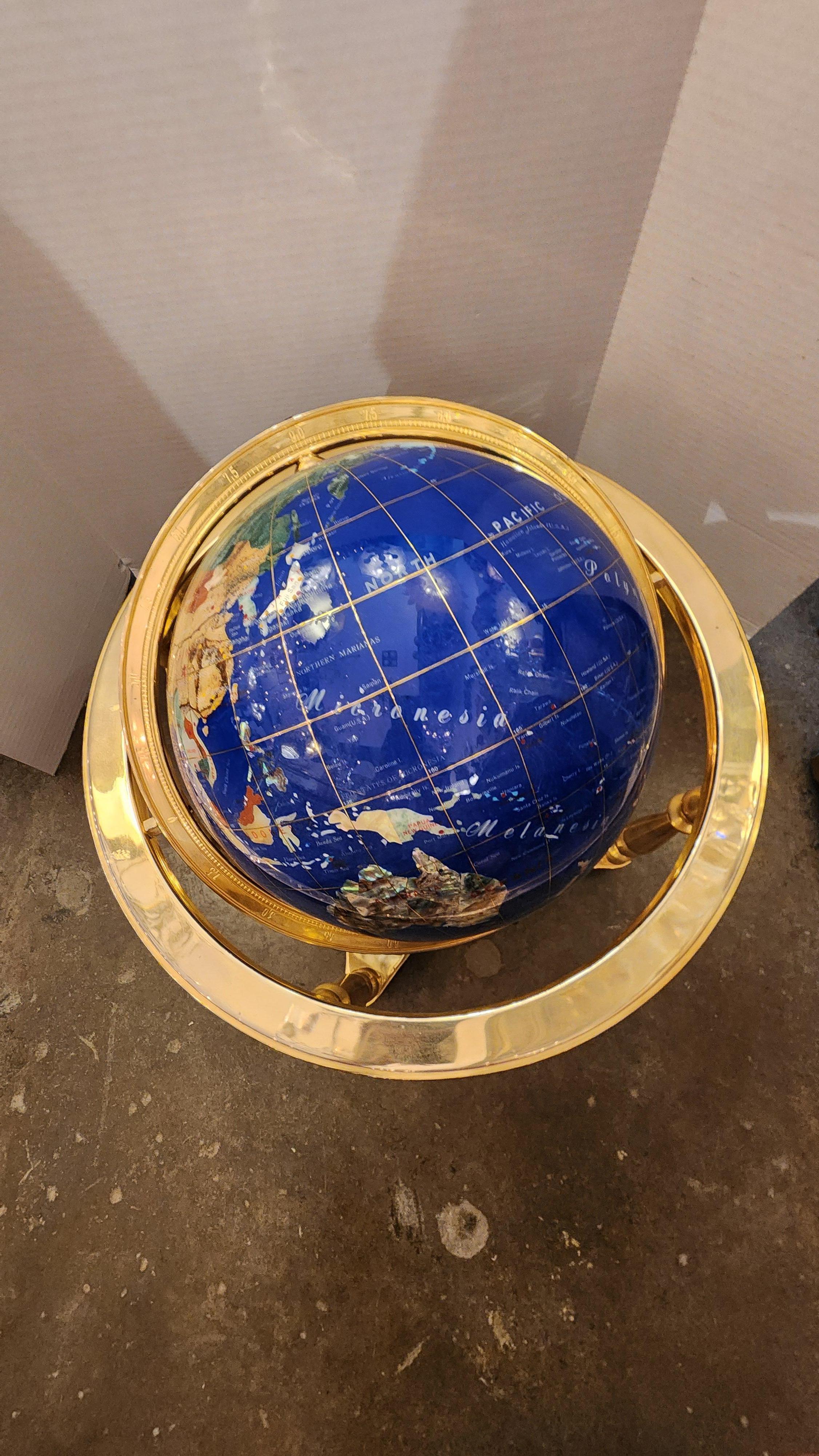 Cette annonce présente un globe rotatif en fausse pierre dure avec un cadre en laiton. Il est entièrement fonctionnel et se déplace sans problème.