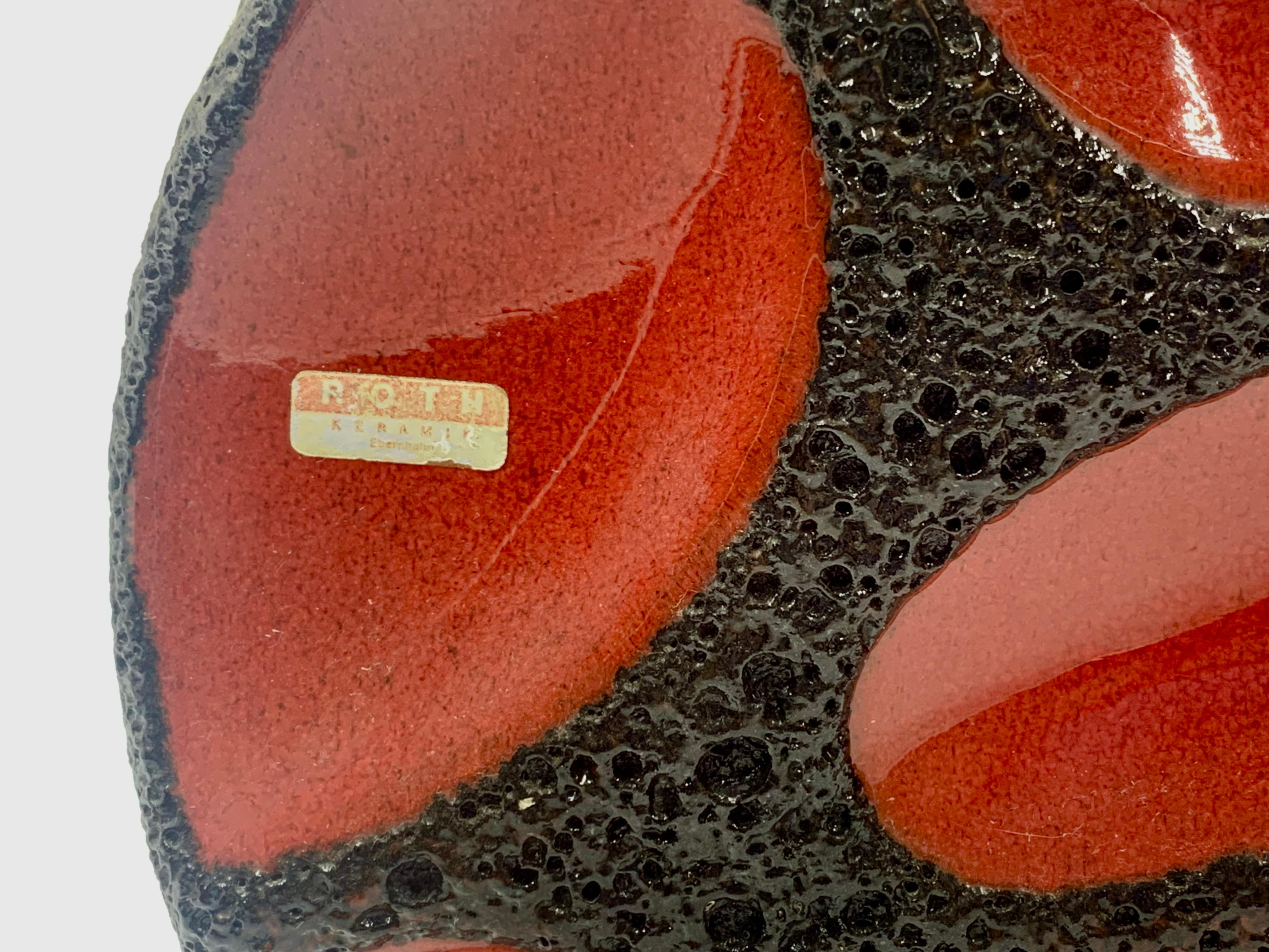 Jarrón redondo plano esmaltado en lava roja y negra Roth Keramik, número de modelo 310. Patrón ovalado rojo brillante y etiqueta de fabricación de papel de aluminio.
Este jarrón está en excelentes condiciones.