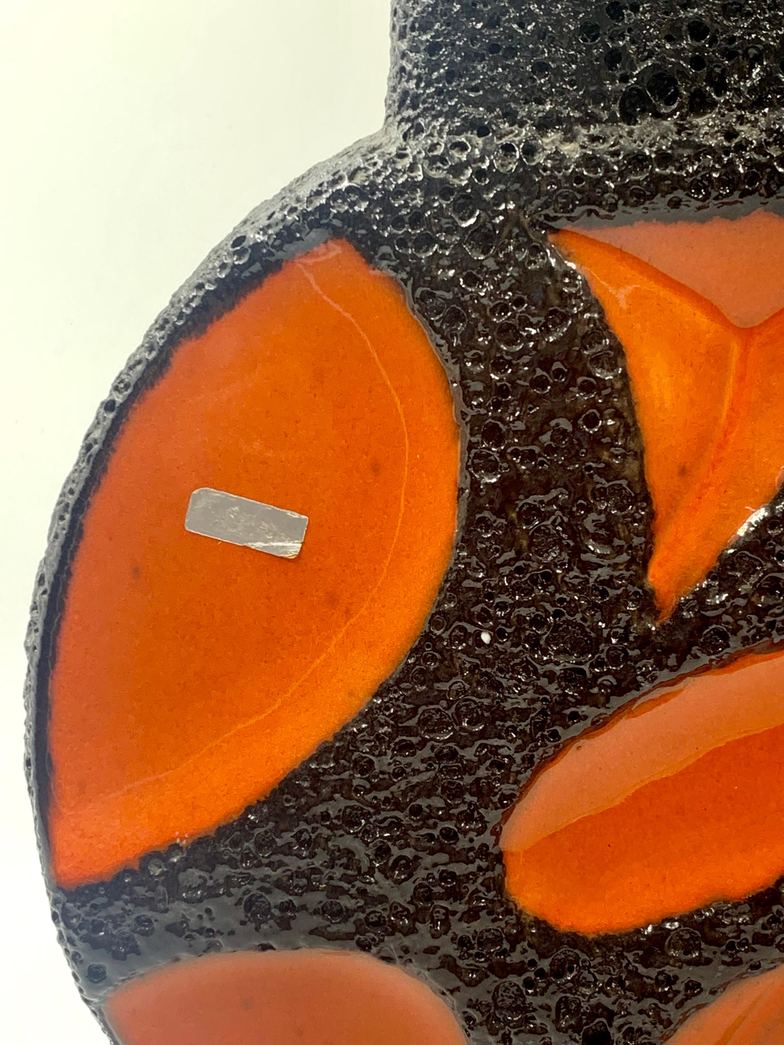 A Roth Keramik large jug vase, 40 cm, in bright orange with a black lava glaze highlighting the coloured panels.
With 2 ring handles and the manufacturer’s label still attached.
A distinctive and impressive retro vase to brighten up even the darkest