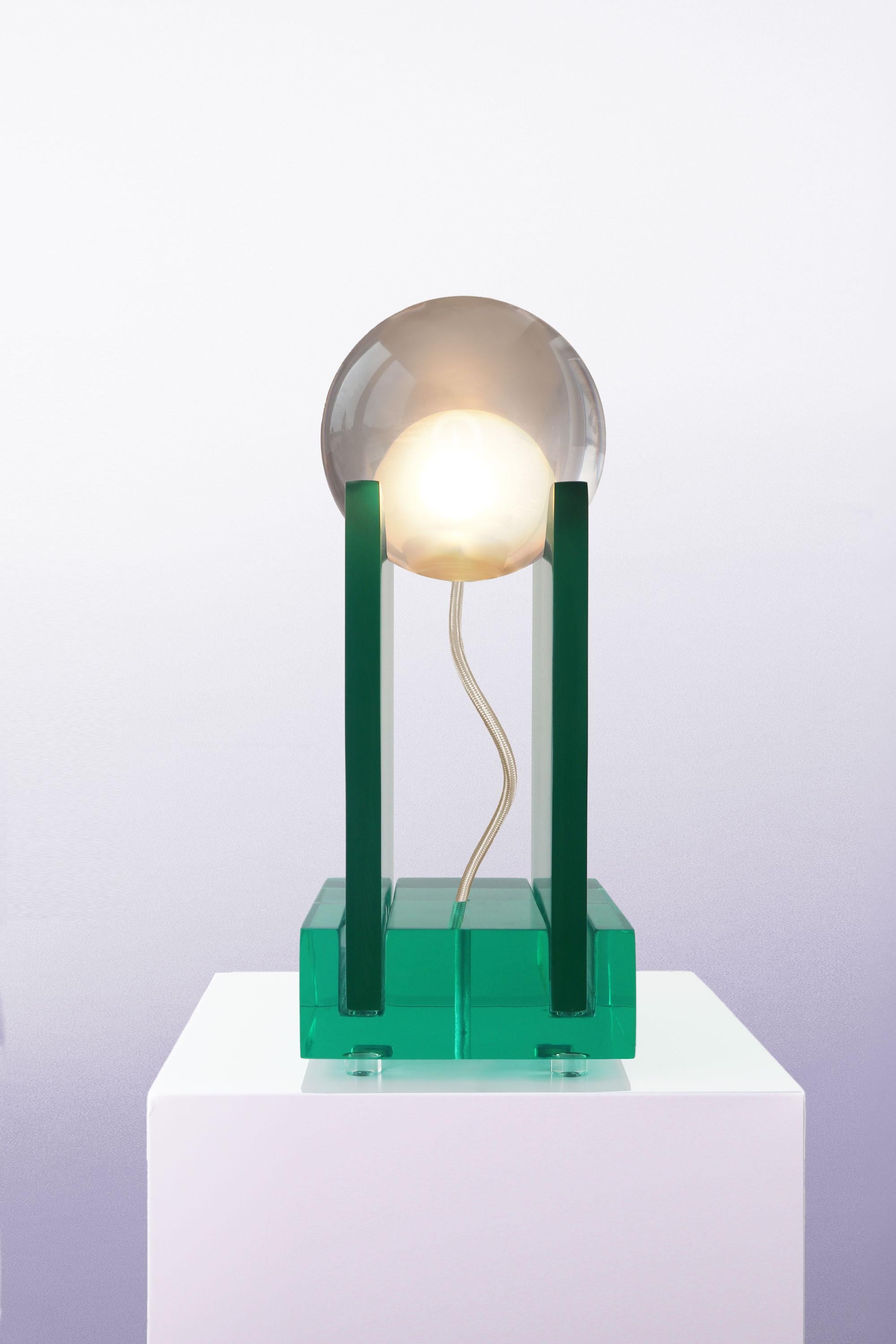Inspired by Renaissance-era floor plans of Italian villas, the bulb of Adrian Cruz's Rotonda Table Lamp is held up by two plates in crystal resin, resting on a pedestal of monochromatic green and displaying a weightless balancing act. Due to