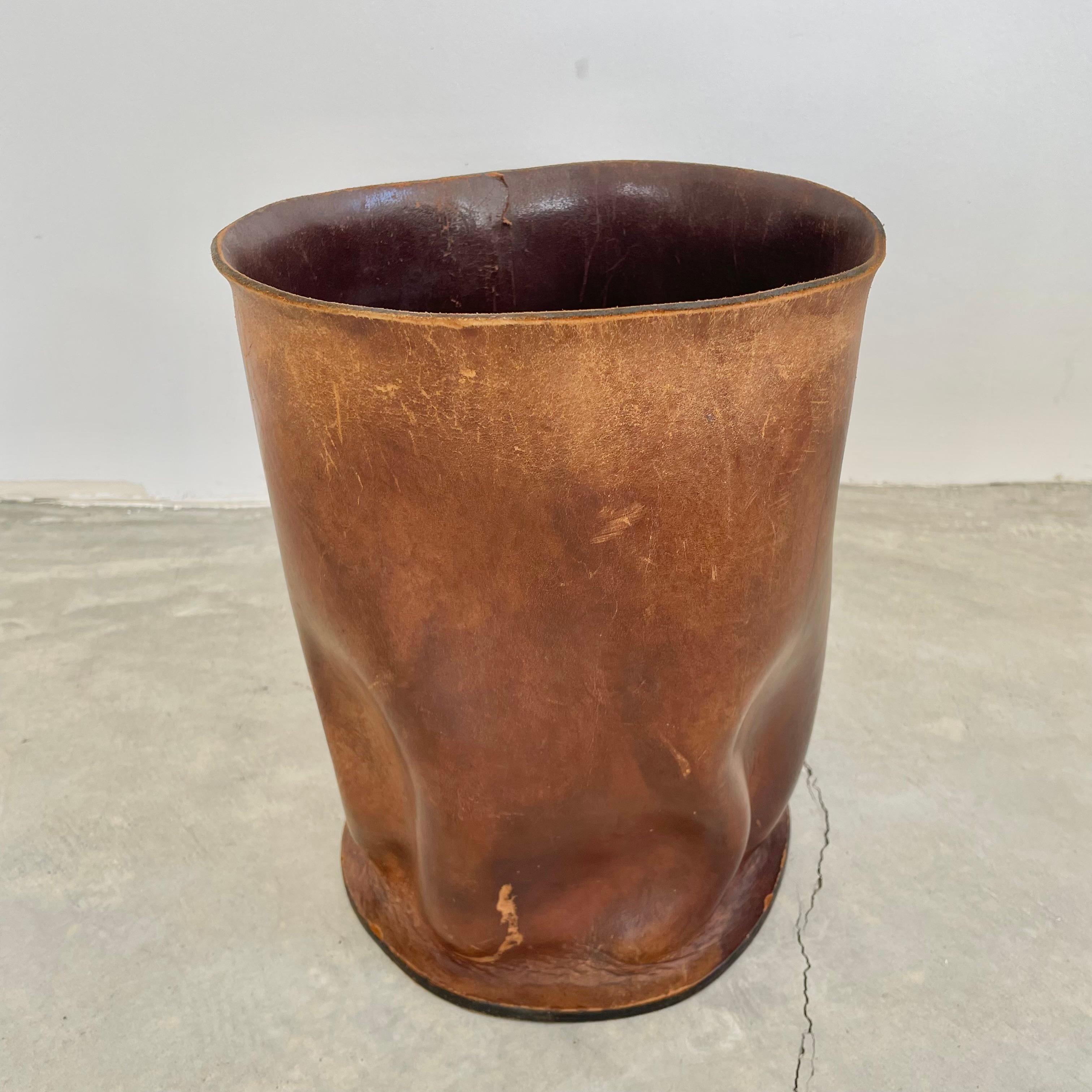 Incredible distressed cowhide waste bin. Leather displays folds and ruffles due to years of wear and use giving it a stunning patina. Interior of bin is finished in a chocolate brown dye which shows cracking and fading giving it a one of a kind