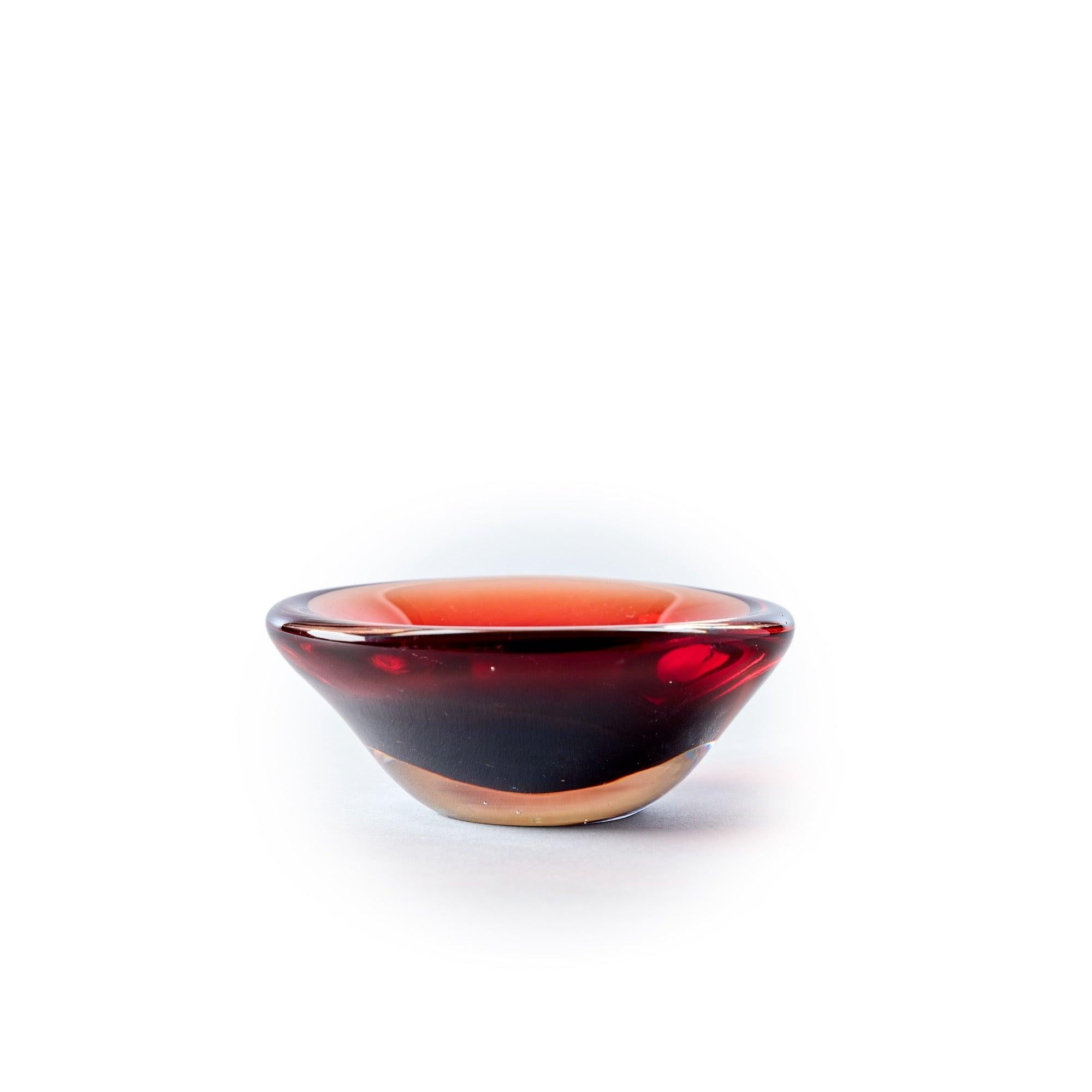 A hand blown glass bowl in blackened rouge with a soft undulating rim.