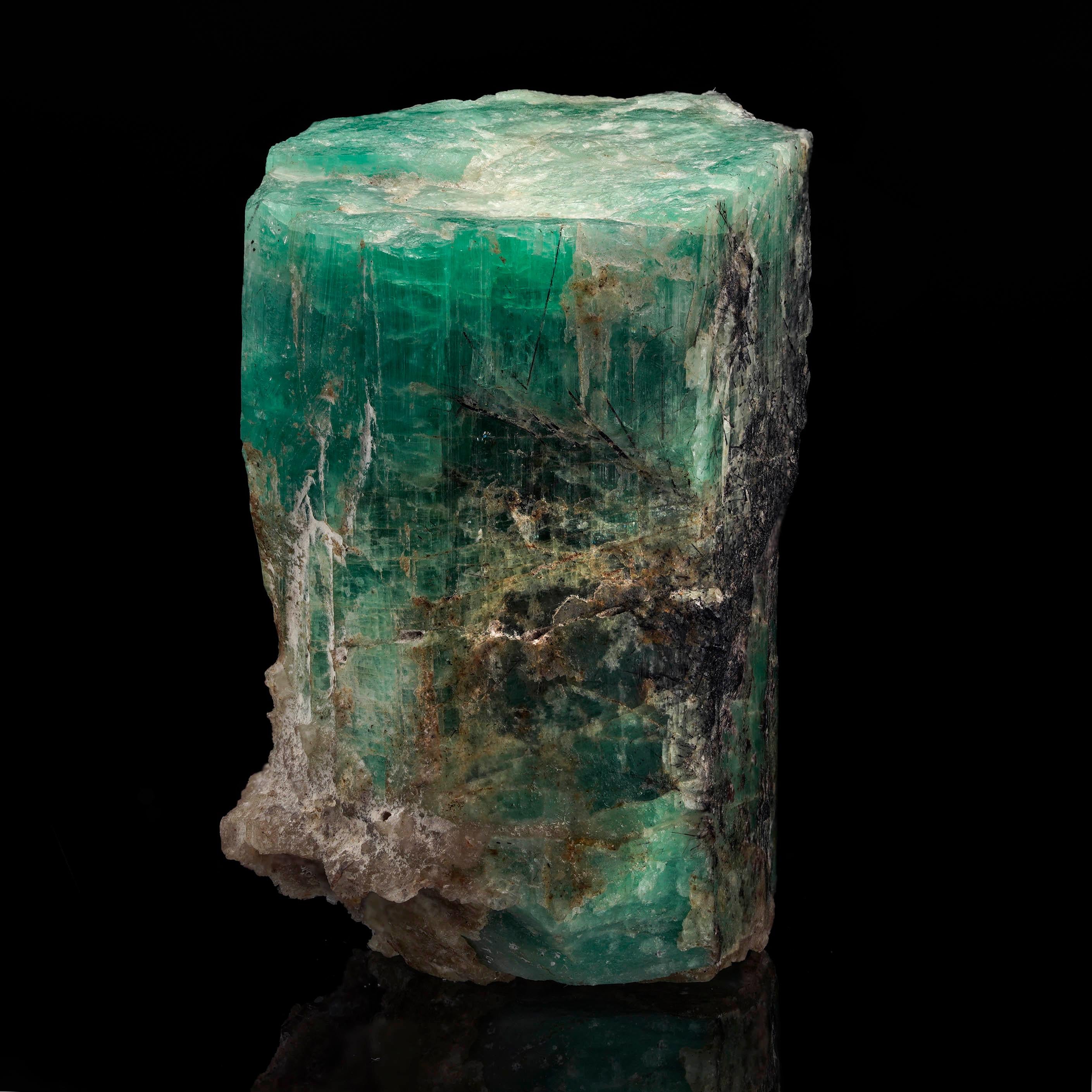 Questo straordinario esemplare di smeraldo grezzo proveniente dalla Colombia mostra una vivida tonalità verde accentuata da inclusioni nere naturali. La sua struttura non raffinata mette in risalto la bellezza grezza degli smeraldi nella loro forma