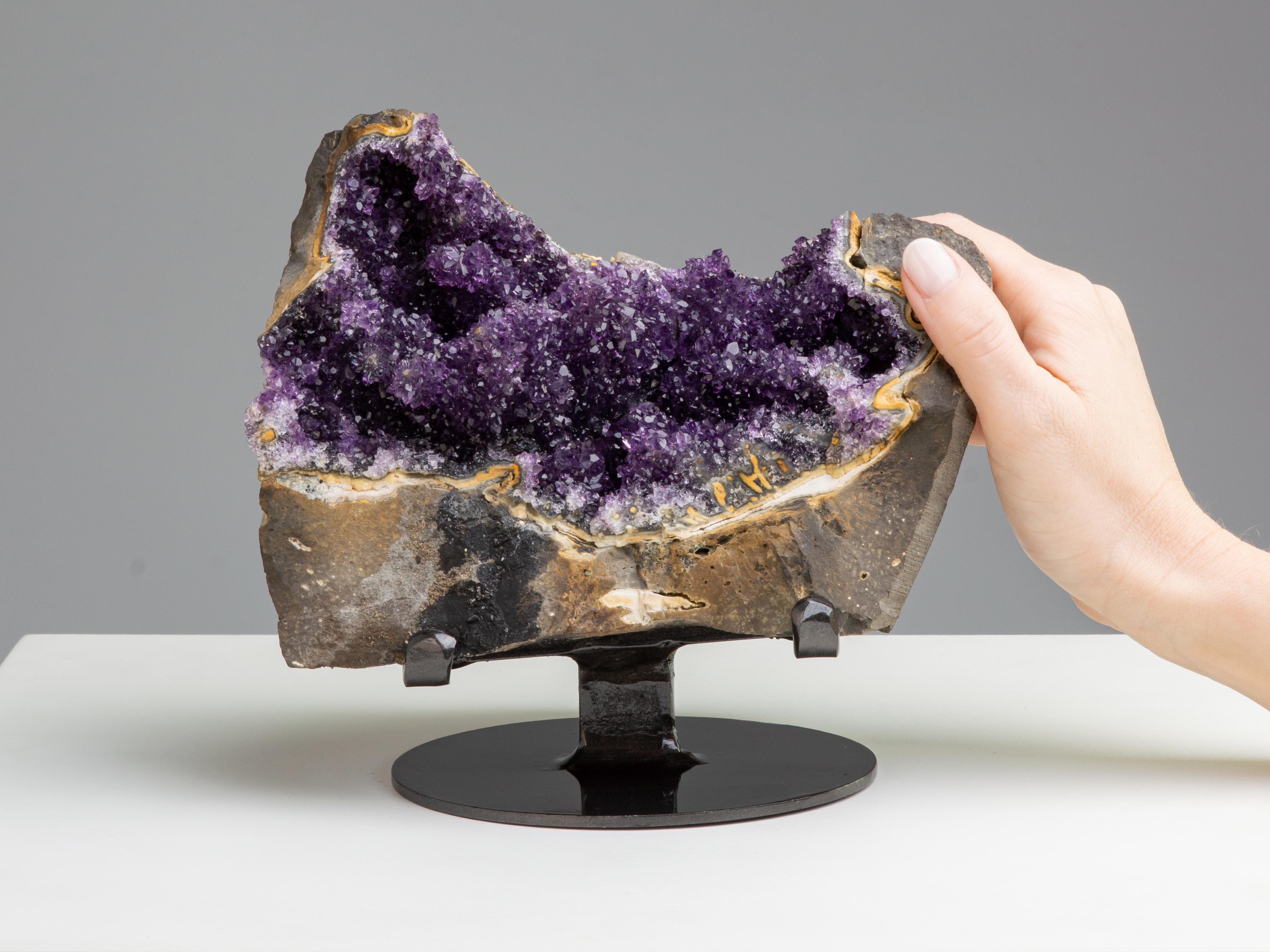Like a treasure chest, this striking geode section shows the incredible
contrast between the rough volcanic stone (basalt) in which the geodes
are found, and the radiant amethystine quartz crystals they conceal.

This piece was legally and ethically