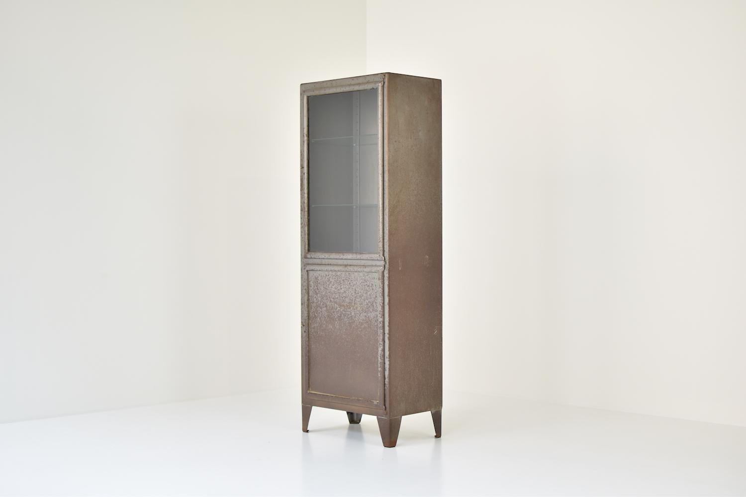 Rough patinated industrial vitrine cabinet, France, 1950s. This cabinet features two storage compartments: an ‘open’ storage with 2 glass shelves and a ‘closed’ one with 1 wooden shelf. Lots of patina!