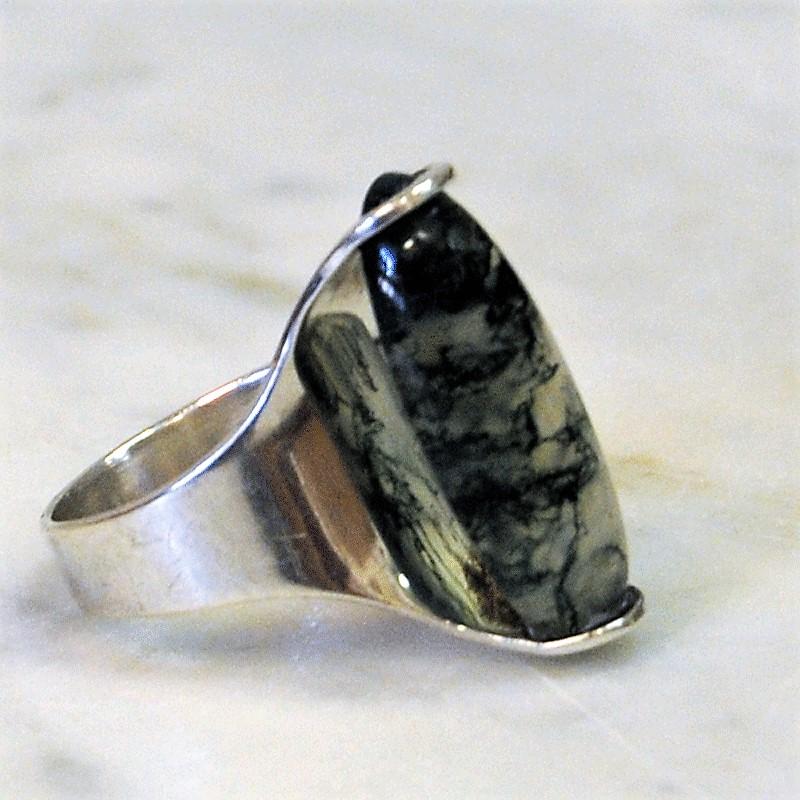 A rougher and massive silvering with a clear long shaped green stone nicely attached to the silver base. Air underneath the stone and ring. From Germany marked 825S.
Measures: Inner diameter is 19 mm, total height of ring 27 mm. Size of stone 22 mm