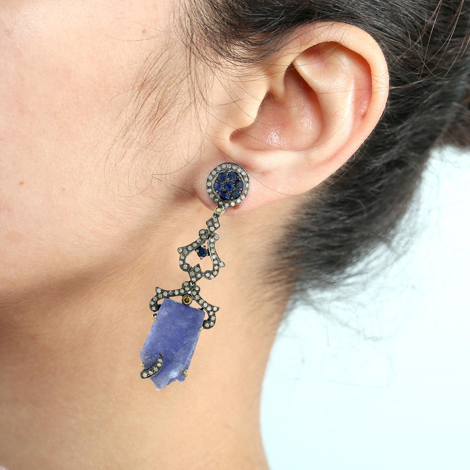 Questi splendidi orecchini pendenti di tanzanite sono una vera e propria opera d'arte. Realizzati a mano con i migliori materiali, questi orecchini presentano una coppia di scintillanti gemme di tanzanite e zaffiri luccicanti. Gli orecchini sono
