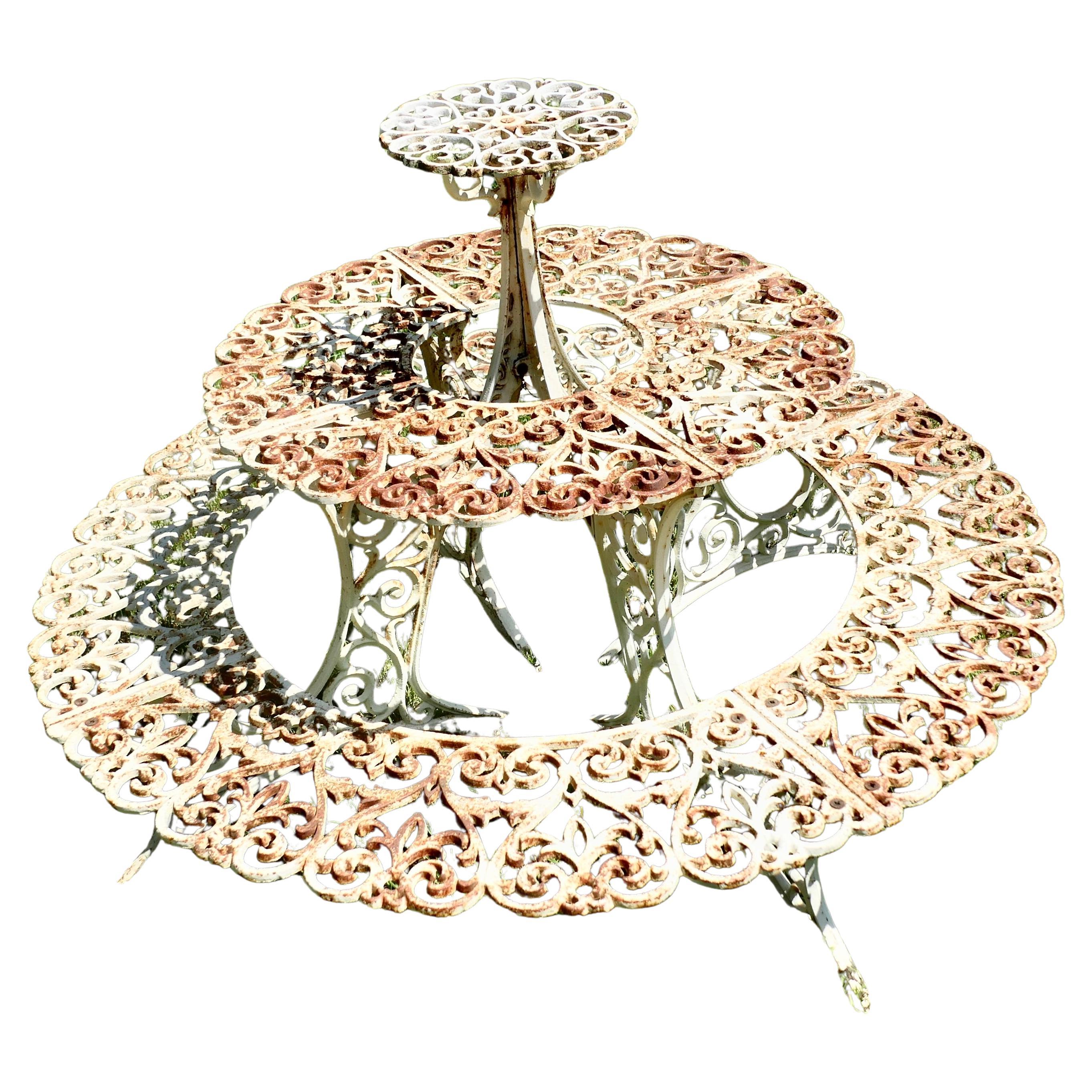 Stand de plantes rond à 3 étages en fonte usée par le temps.