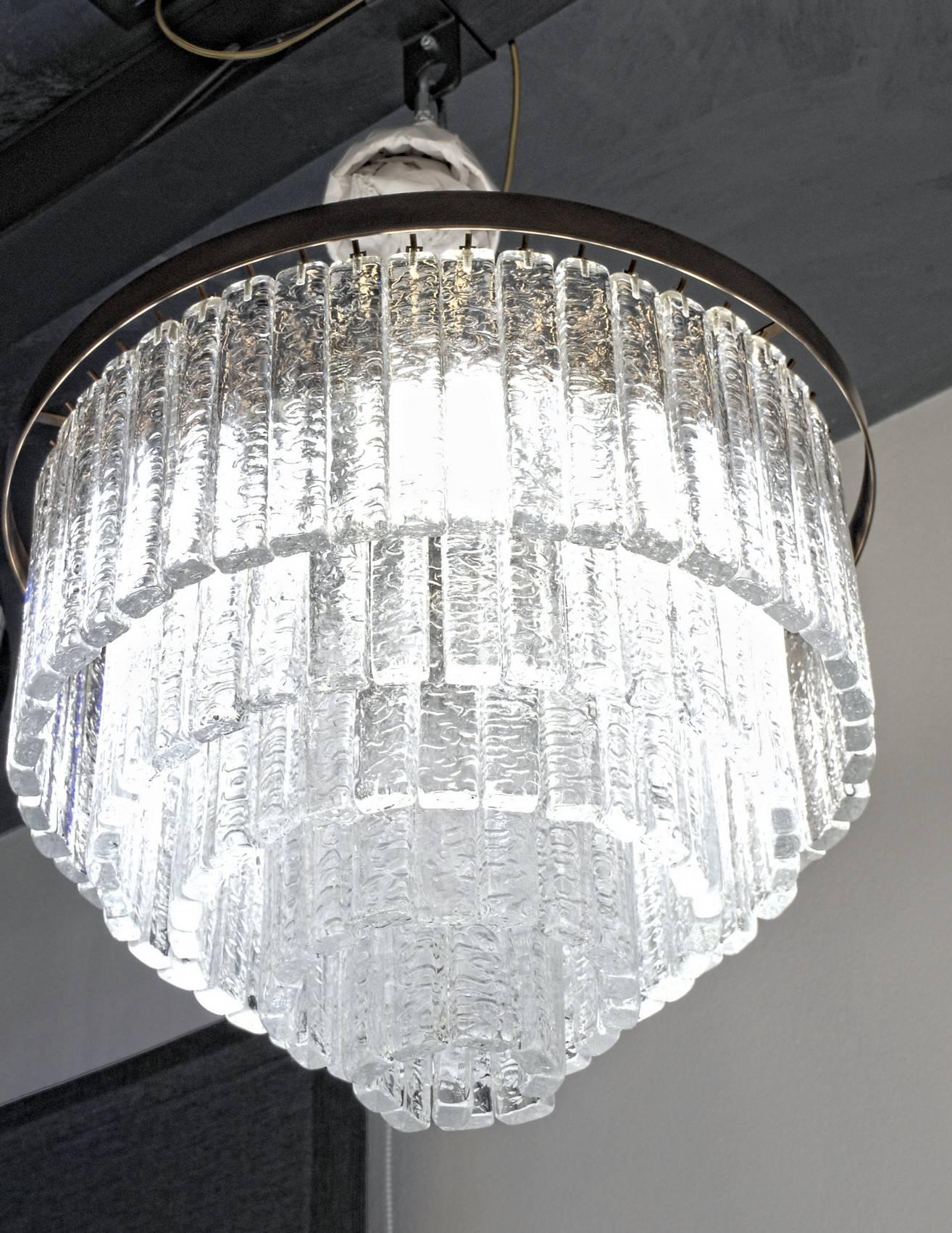 This dense and luxury midcentury chandelier carries around 140 glass elements. Each element has small grooves that are giving the appearance when lit to be white. Because it's a diffraction white appearance it is not reducing the light output as a