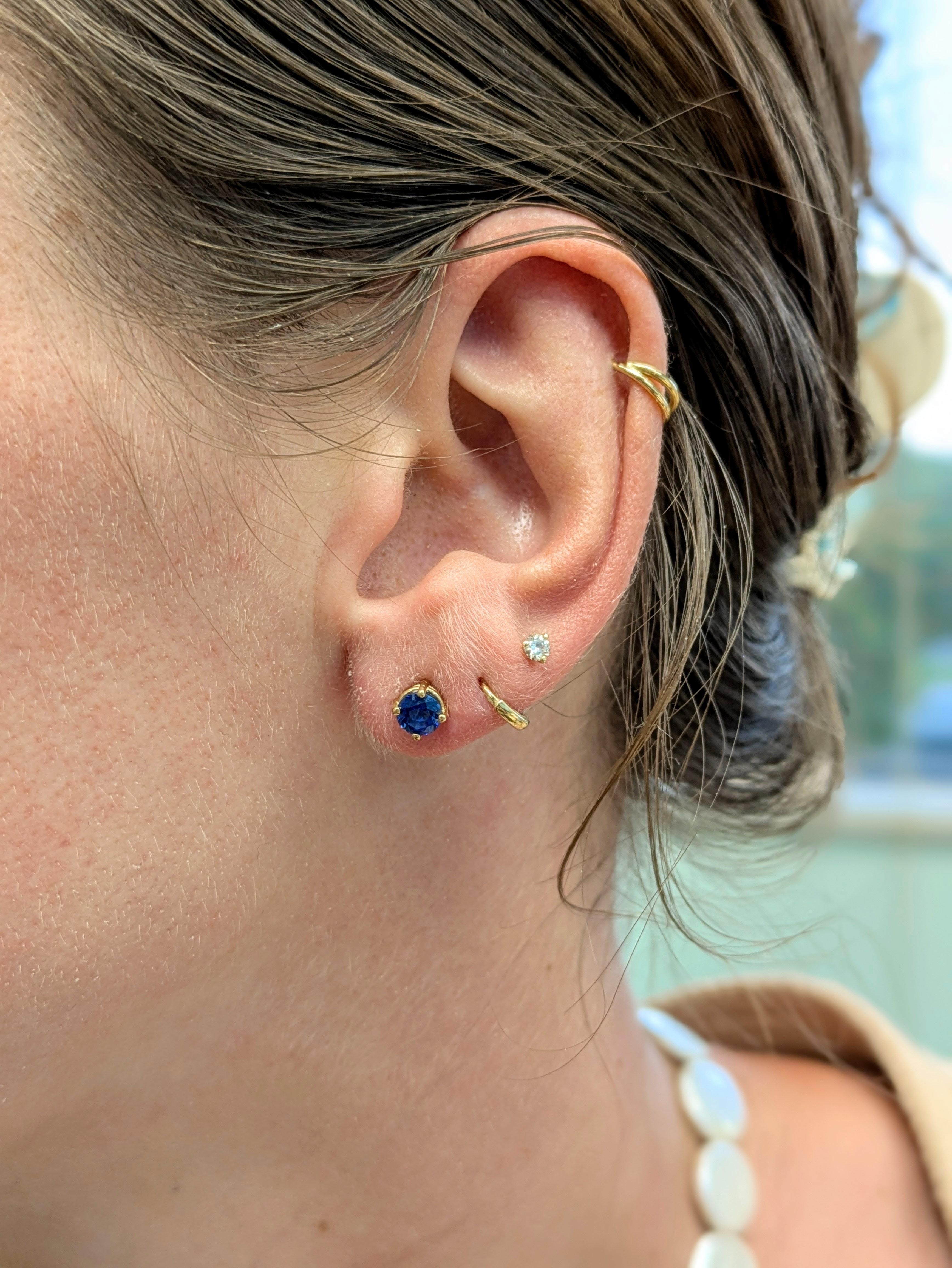 Minimales et intemporelles, ces boucles d'oreilles solitaires en saphir de Ceylan AAA sont réalisées en or massif 14k. Les saphirs ronds de 5 mm de diamètre, montés sur 4 griffes, constituent un cadeau magnifique pour quelqu'un de spécial - ou un
