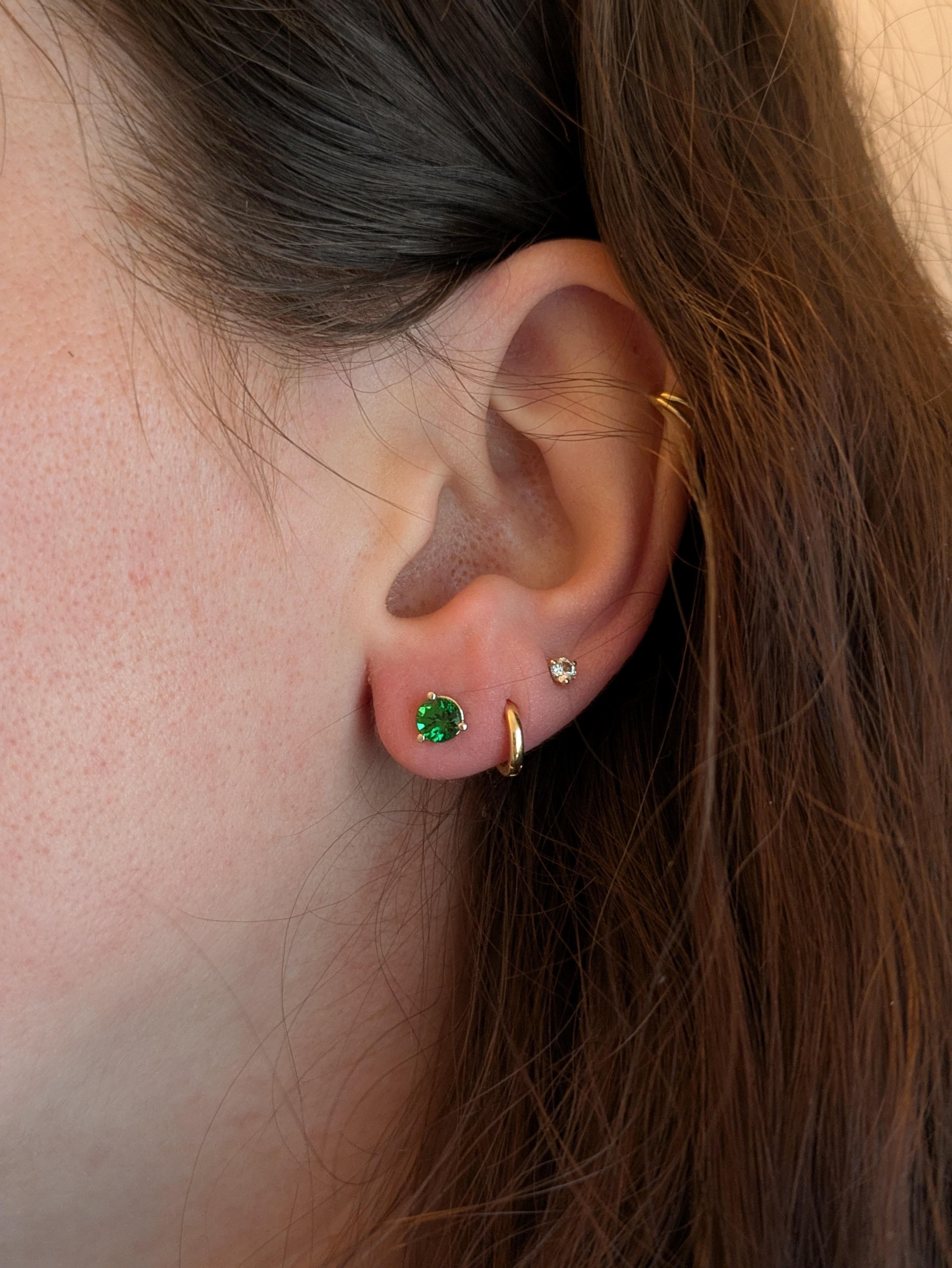 Verleihen Sie Ihrem Alltagsstil mit diesen Solitärohrsteckern mit Tsavorit aus massivem 14-karätigem Weißgold einen leuchtenden Hauch von Grün. Die 5 mm großen, runden Edelsteine glänzen mit einem satten, natürlichen Glanz, während die schlanke