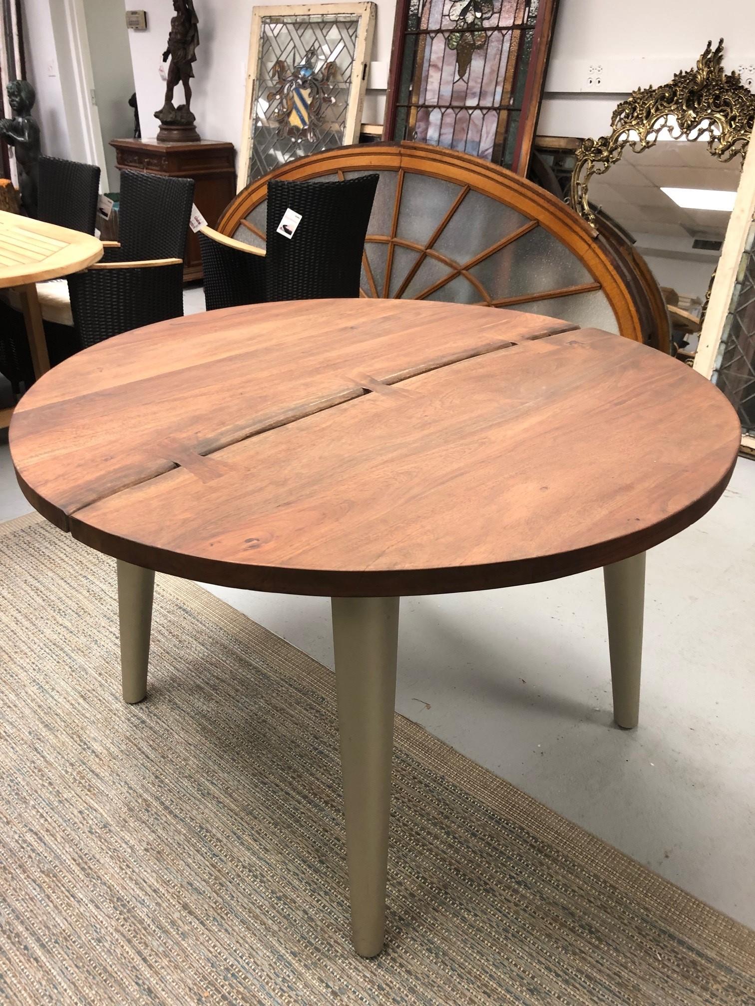 Round Acacia wood dining table on four legs with a live edge center cut. Acacia wood is a hardwood from India that looks like walnut beautiful and durable.