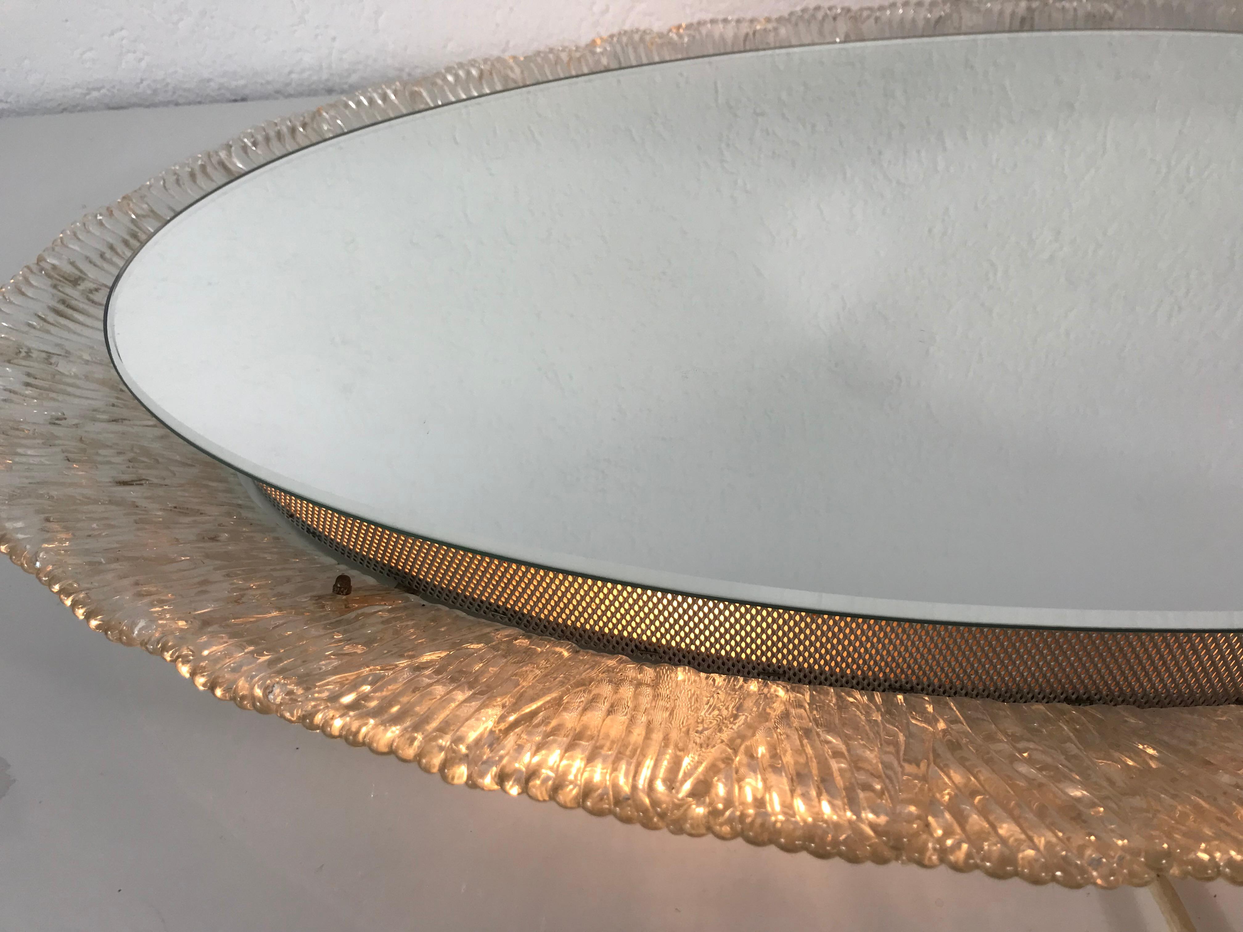 An illuminated wall mirror from the German manufacturer Hillebrand Lighting. It was made in the 1970s. The mirror has a oval acrylic design. There are E14 light bulbs inside the frame. The mirror is in a good vintage condition.