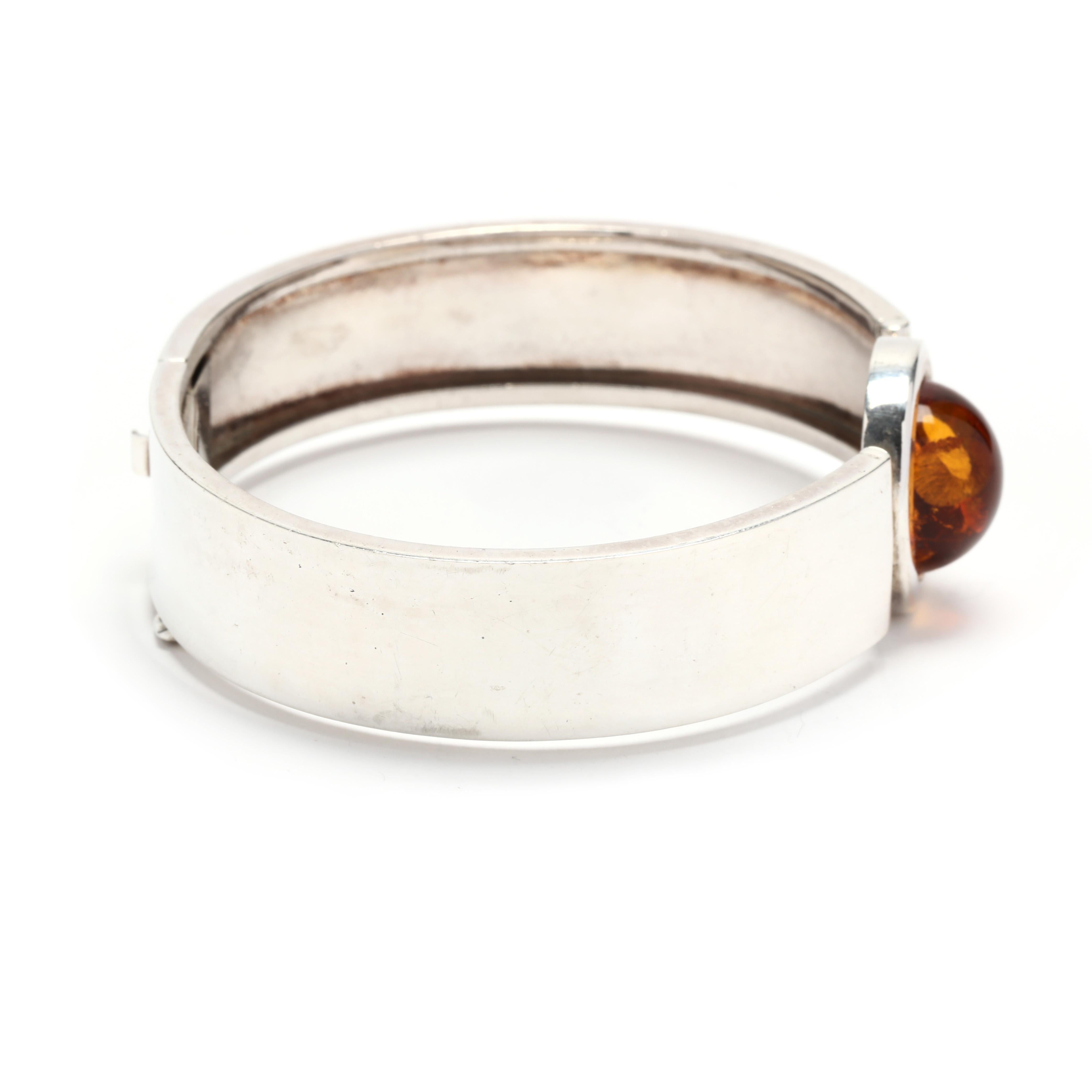 A vintage sterling silver round cabochon amber bangle bracelet. This stackable bracelet featuring a central bezel set oval cabochon amber joined to a flat silver bracelet with an integrated clasp and safety catch.  It is stamped 925.

Stones:
-