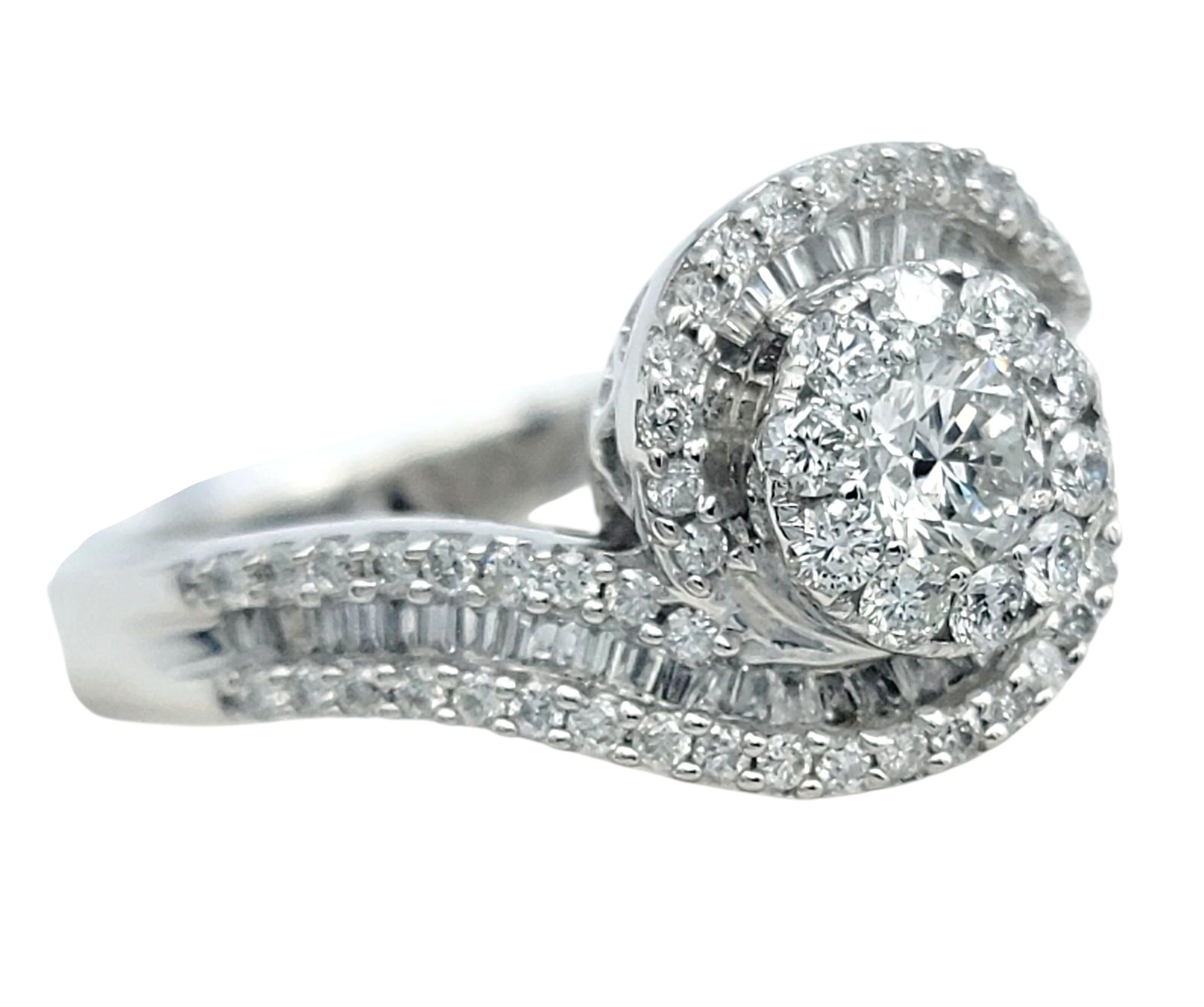 Cette élégante bague en diamant est réalisée en or blanc 14 carats et présente un mélange de diamants baguettes et ronds. Le design s'articule autour d'un diamant rond encadré d'un halo, tandis que d'autres rangées de diamants se succèdent le long