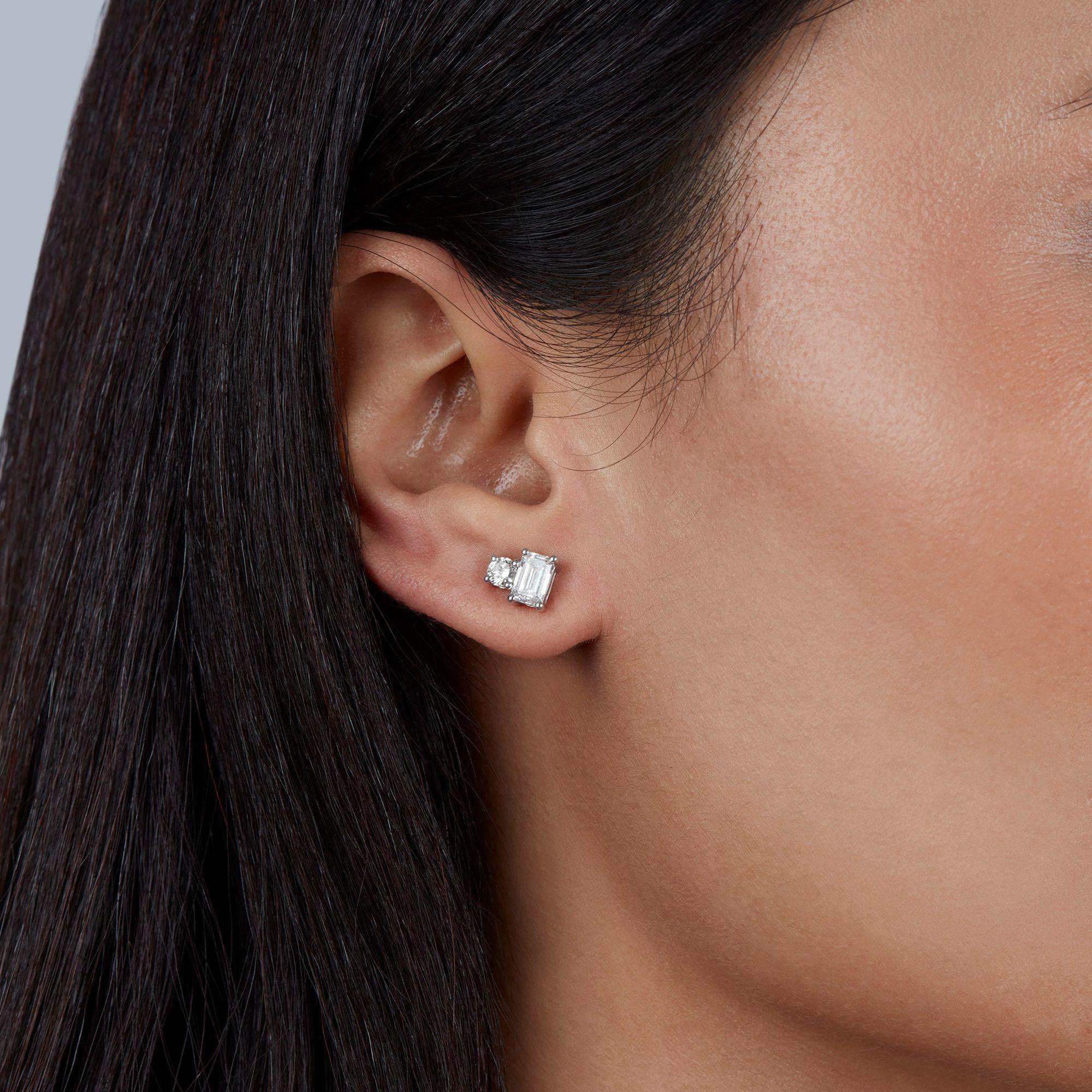 A modern take on the classic toi et moi style—these diamond stud earrings pair an emerald-cut diamond with a round diamond for a bold, balanced look. The emerald cut gives clean lines and depth, while the round diamond adds sparkle and shine. Set in
