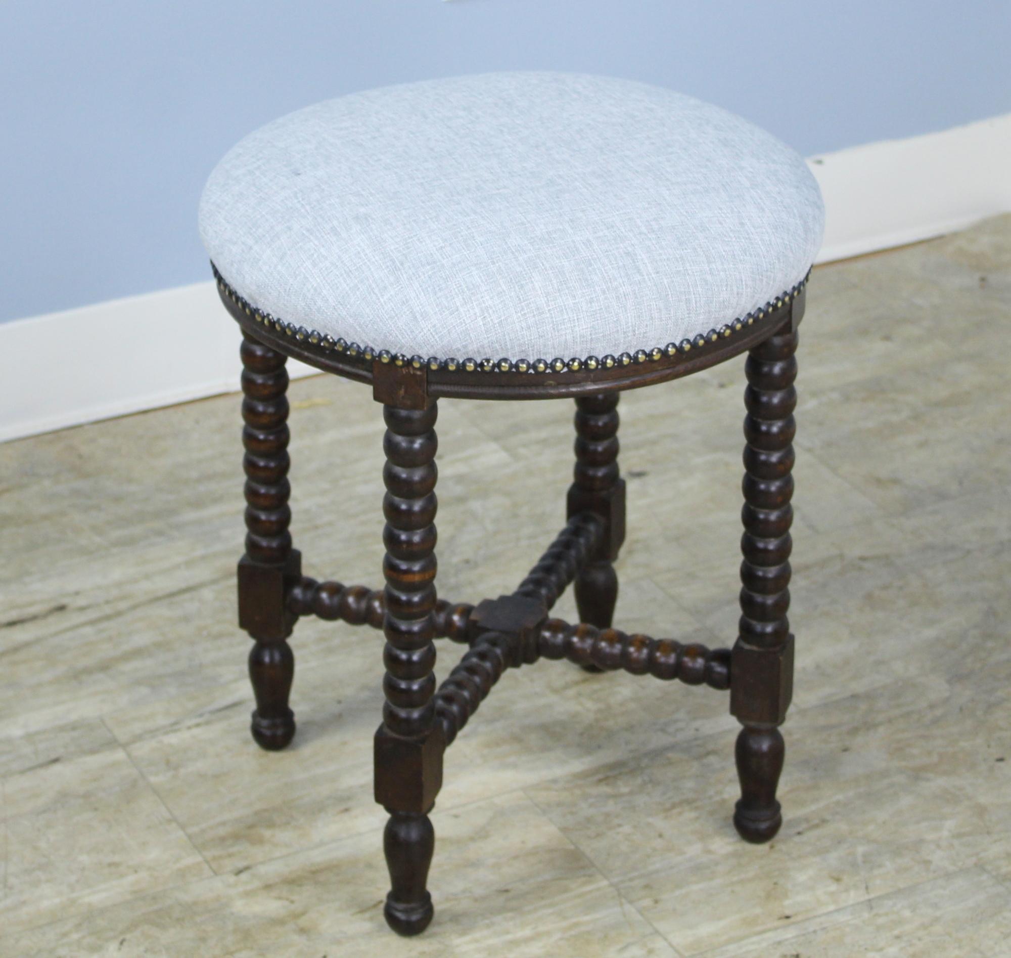 An eye-catching bobbin legged stool, newly upholstered in gray linen. Nice comfortable height provides good extra seating in any room. If you need more than one, take a look at our oval stool, similarly upholstered.
