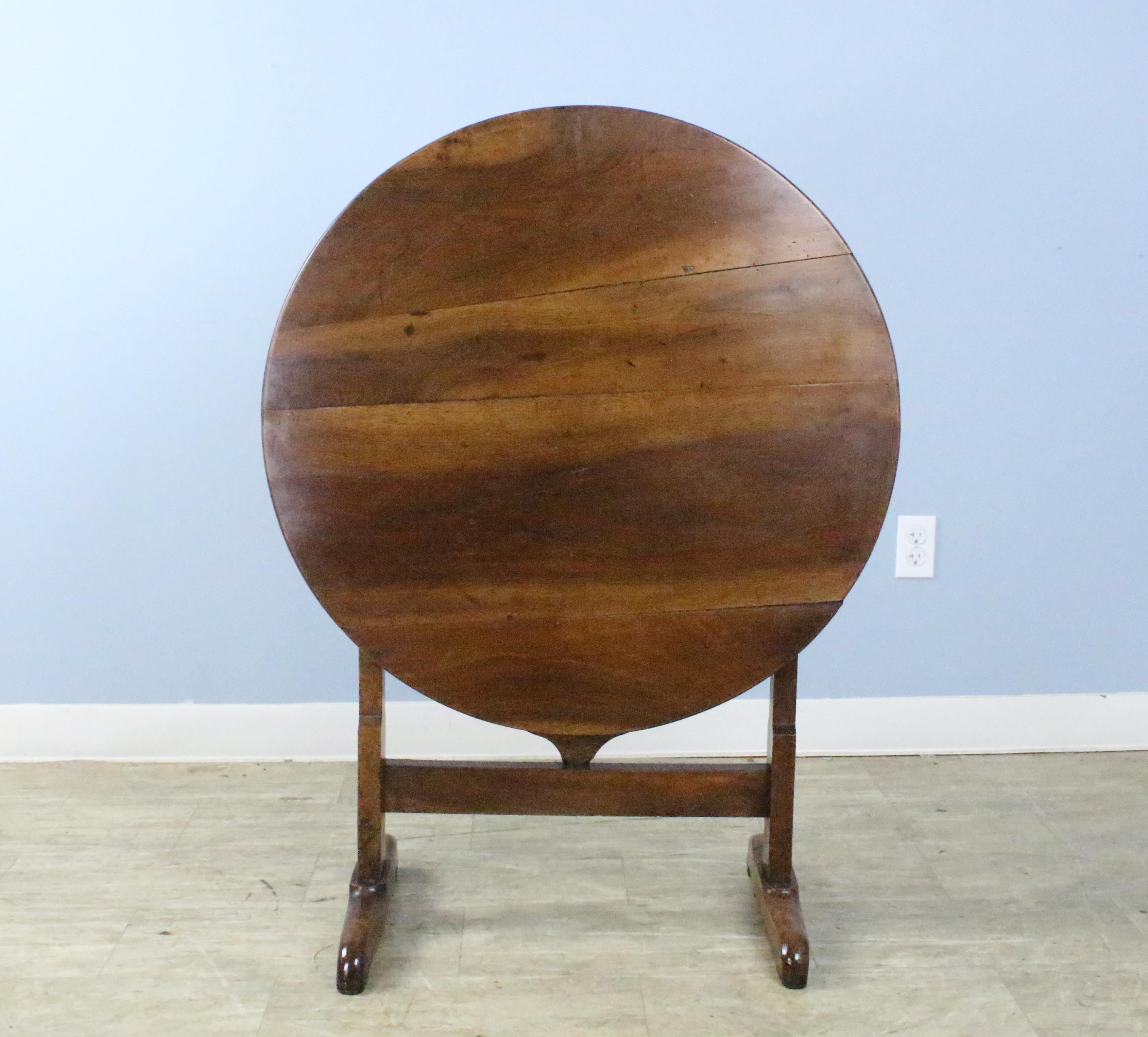 The walnut graining on this very good vendange wine tasting table is quite wonderful. The thick top has a nice patinated edge. The whimsical swivel gateleg table base is easy to use and is sturdy. The table can be stored upright if required, but